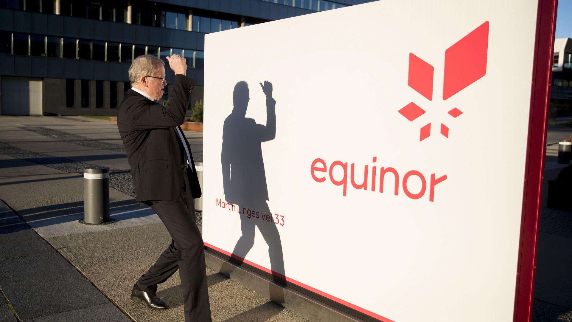 Equinor CEO looking at his shadow on an Equinor sign.