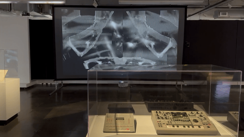 Visuals are shown on a screen, with intersecting black and grey shapes.