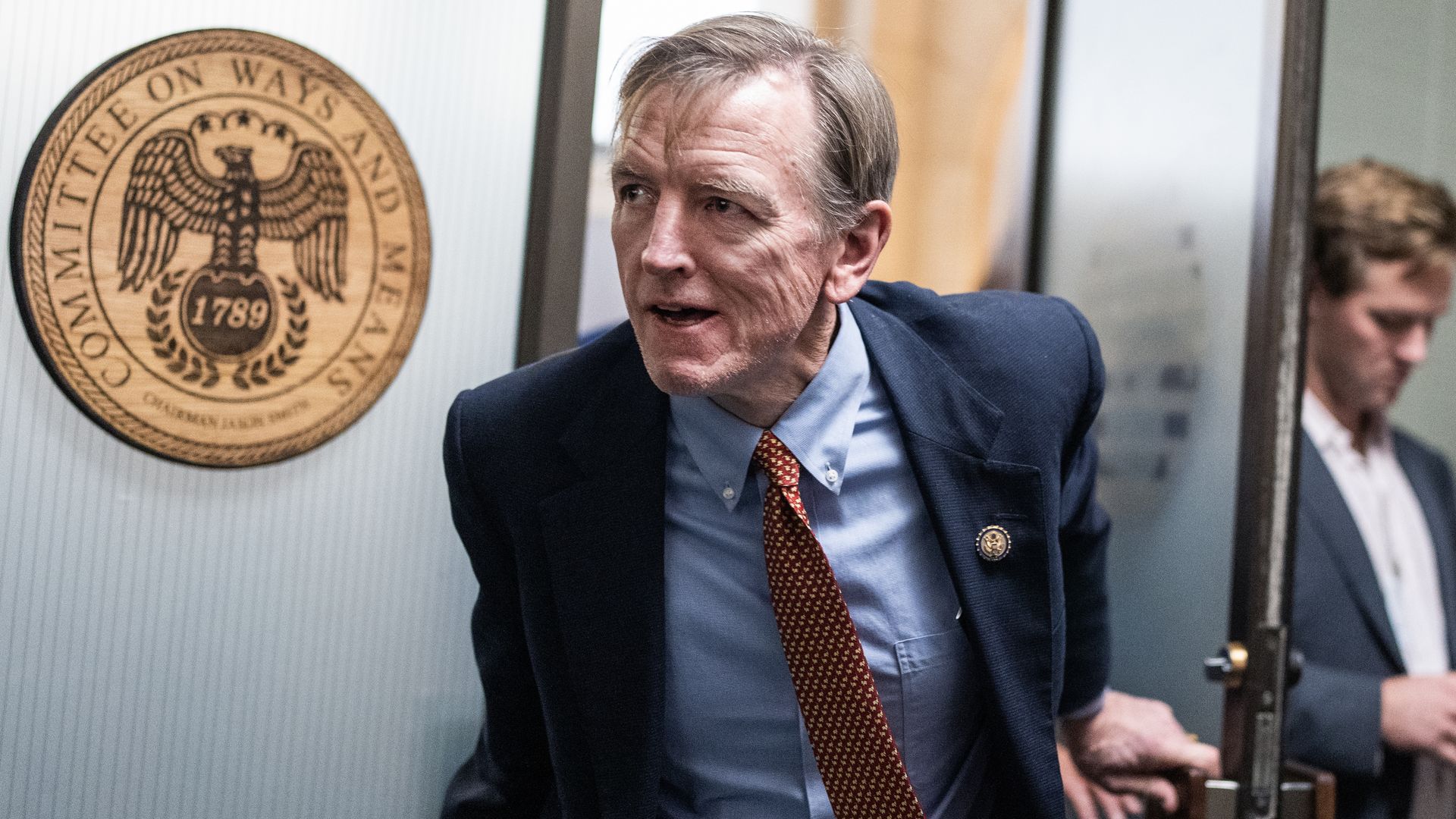 Rep. Paul Gosar, wearing a blue suit and stepping out of a glass door.