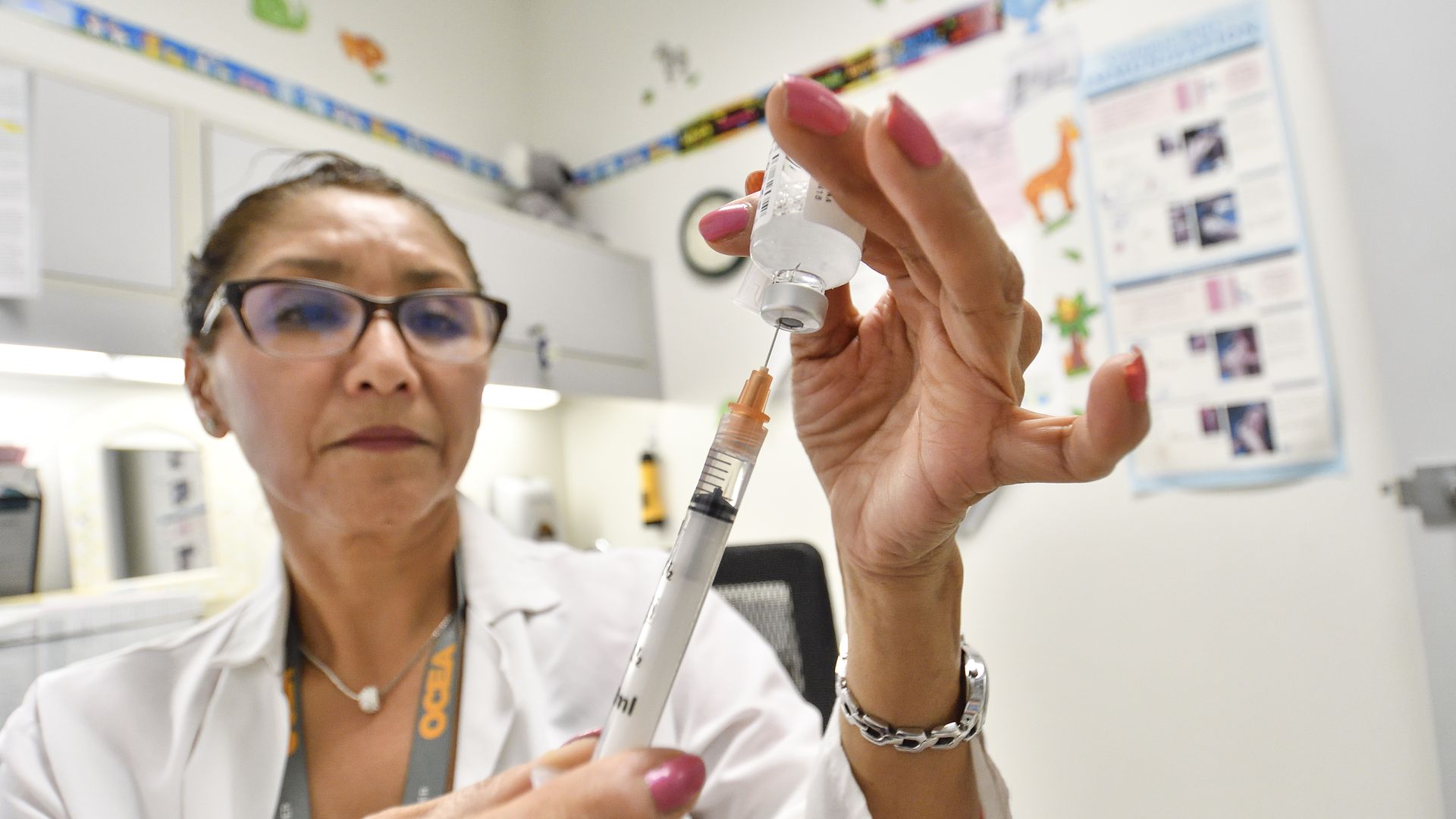 A nurse fills a syringe with the flu vaccine.