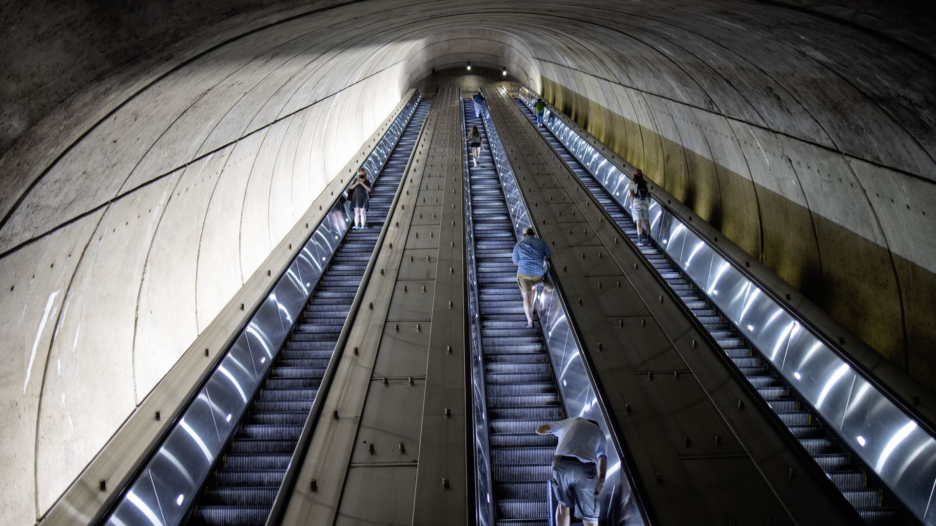 People ride an escalator in and out of a Metro station.