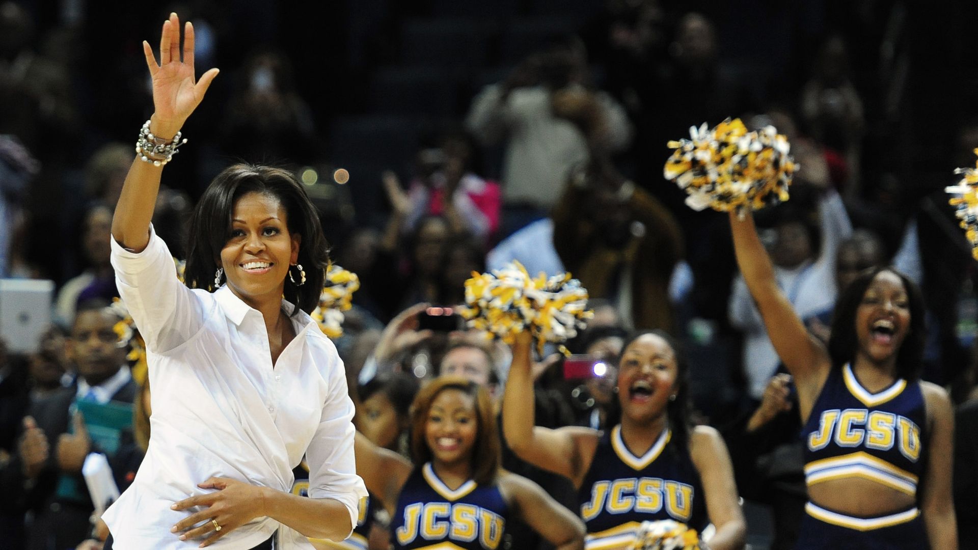 Michelle Obama waves to the crowd as members of the Johnson C. Smith University cheerleaders cheer