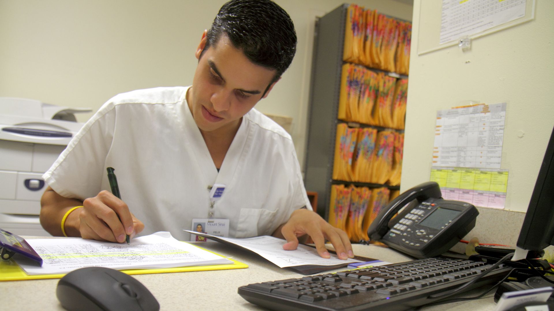 A man at the front desk of a doctors office signs forms