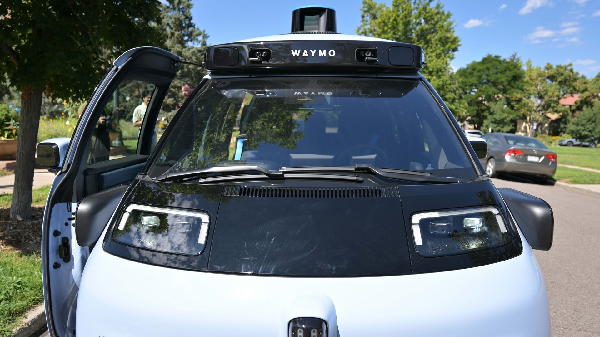 A light blue and black robotaxi equipped with sensors