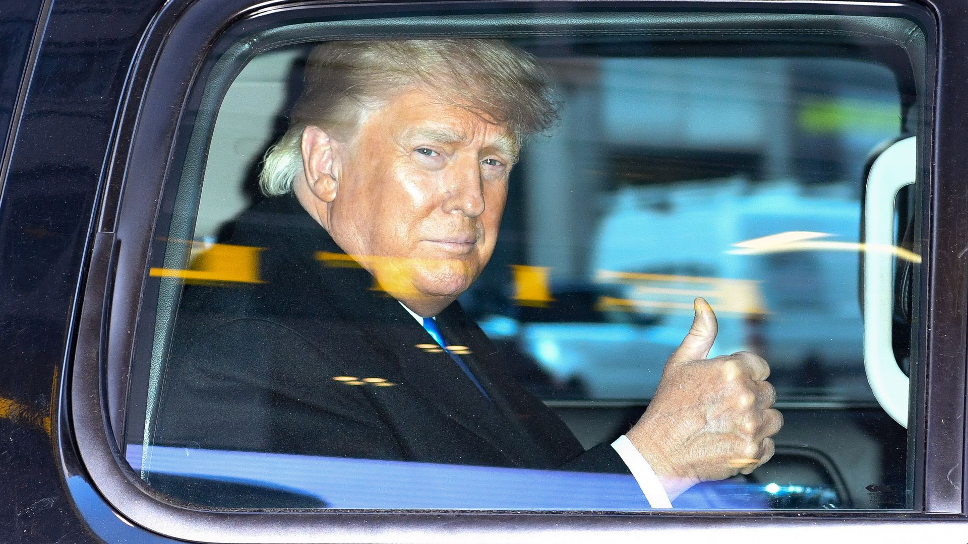 A photo of former President Donald Trump looking out the window of a vehicle. 