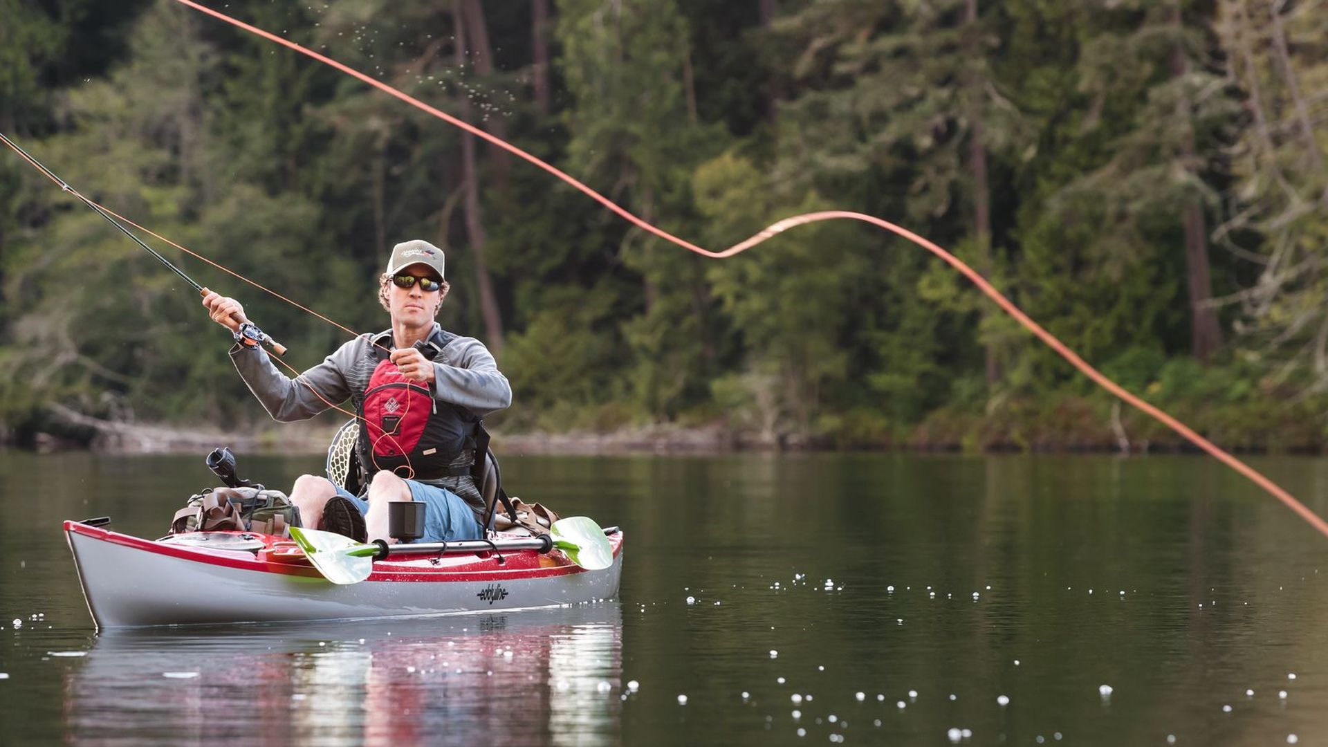 A man fishes from a kayak on a river. 