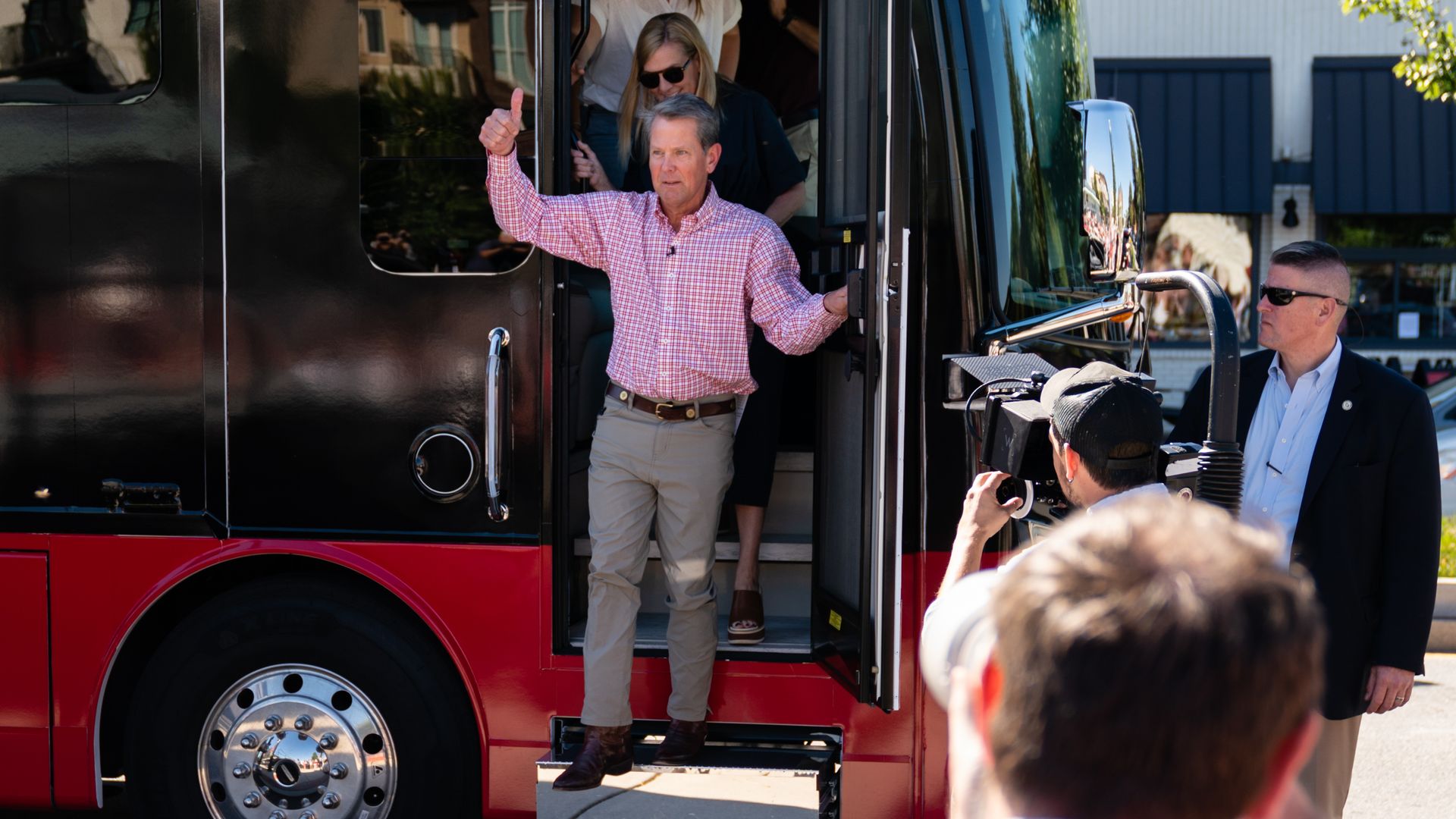 Brian Kemp gives a thumbs up as he steps out of a campaign bus