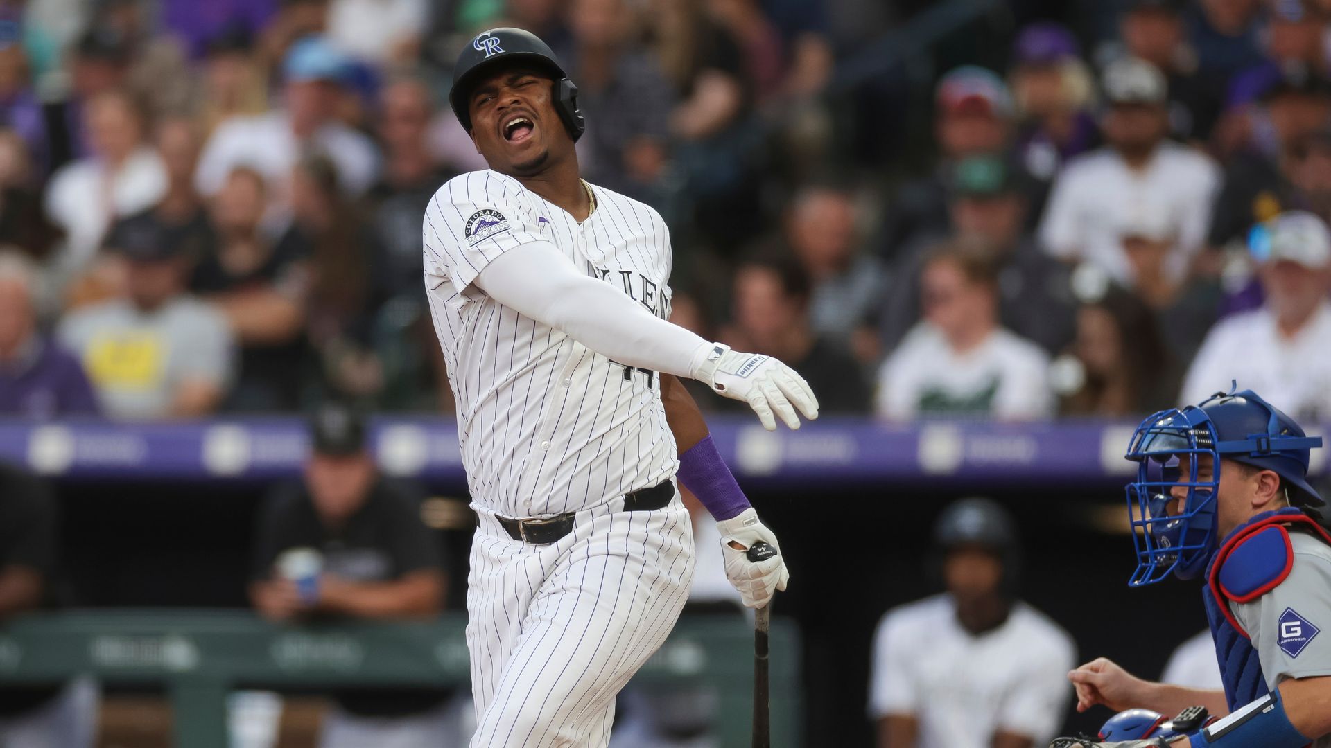 A man in a pinstripe jersey and pants reacts frustratingly after missing a pitch while holding a bat during a baseball game. 