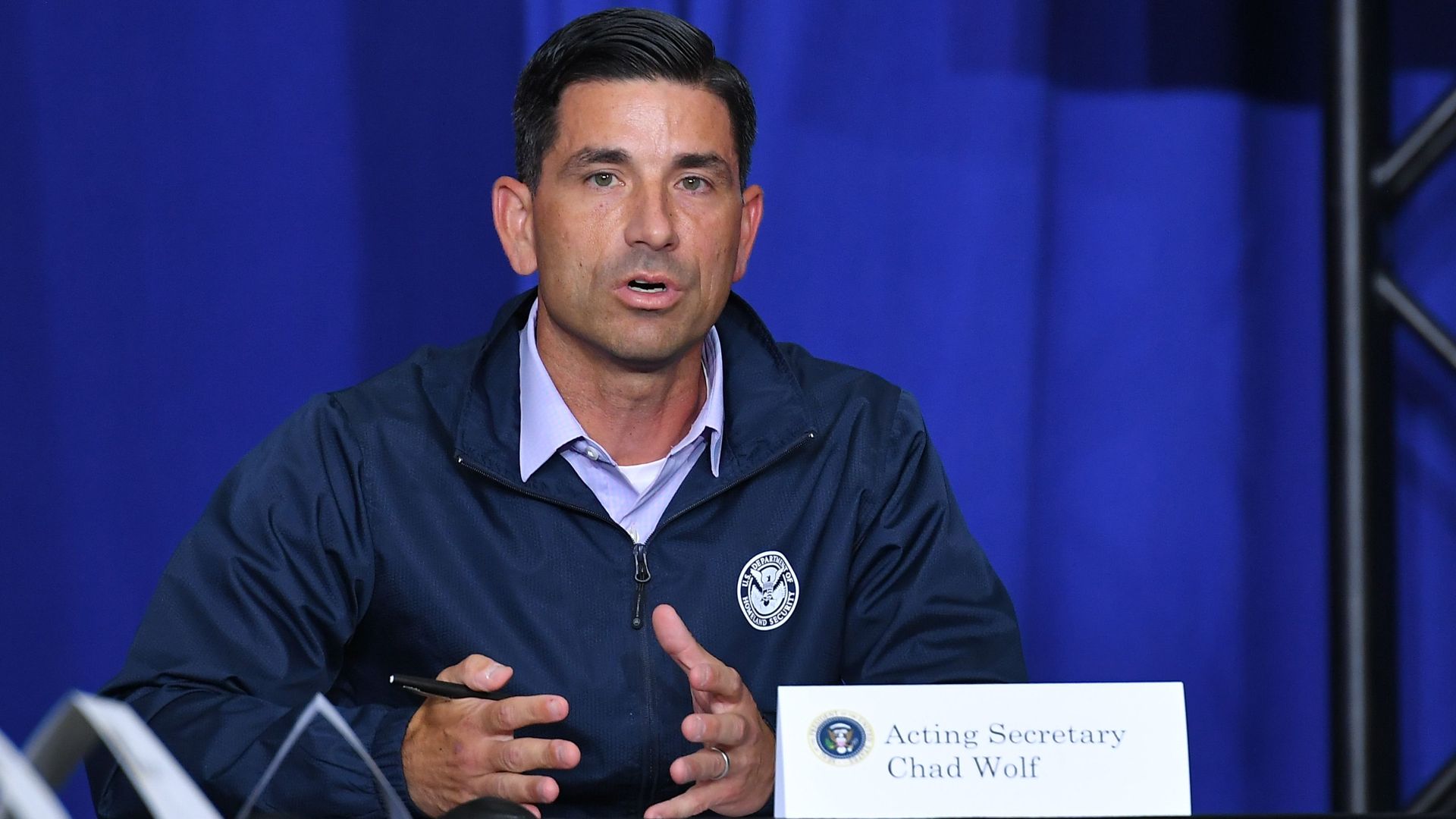 Chad Wolf sits in a windbreaker