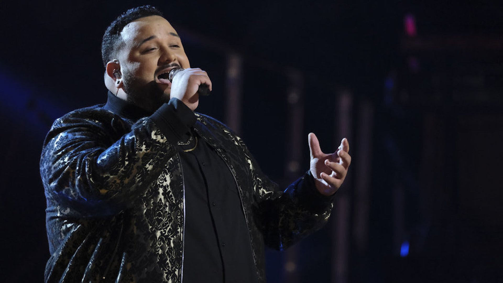 Jeremy Rosado performing on "The Voice" in a black and gold suit.