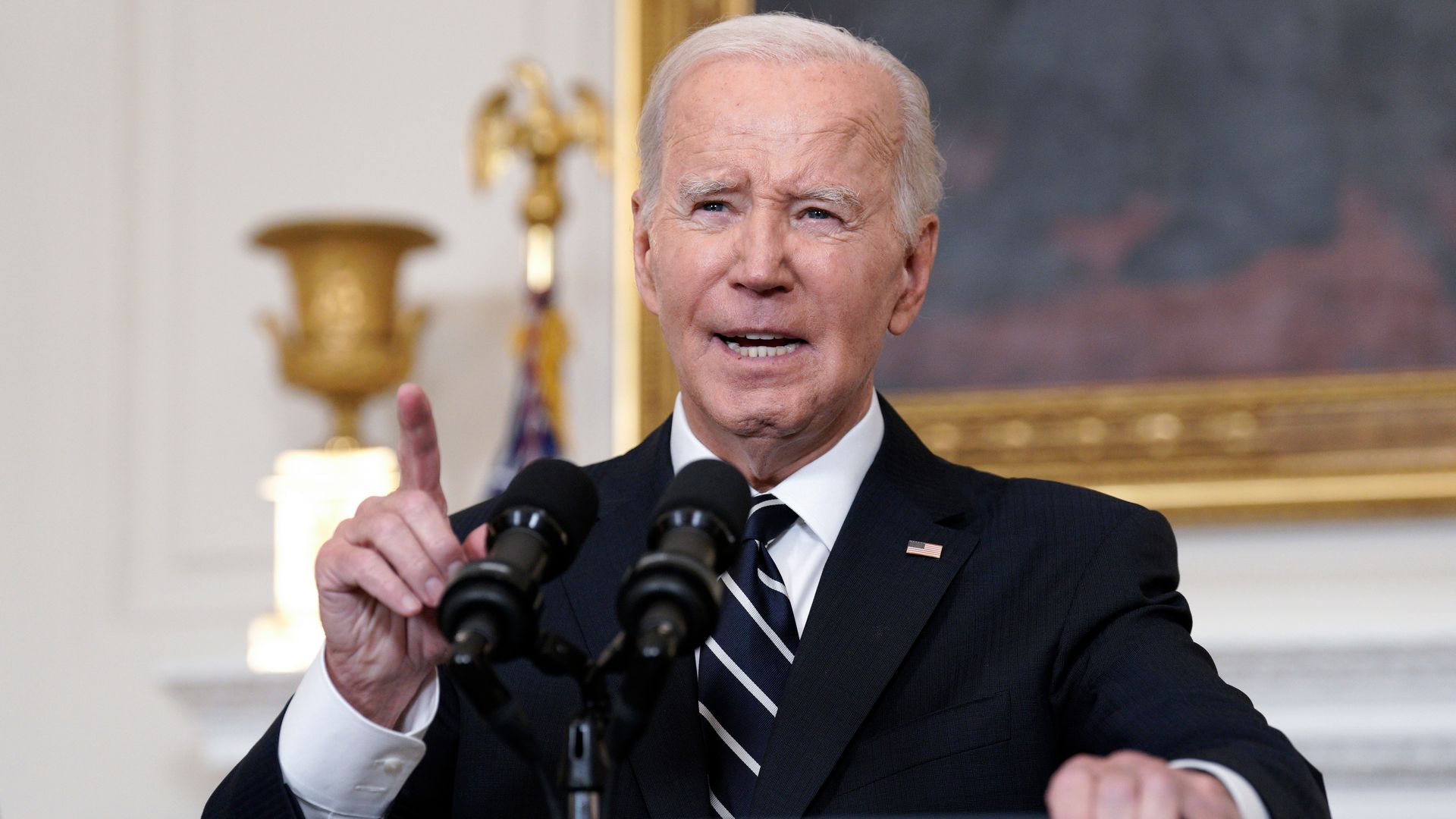 President Biden speaks behind microphones at the White House.