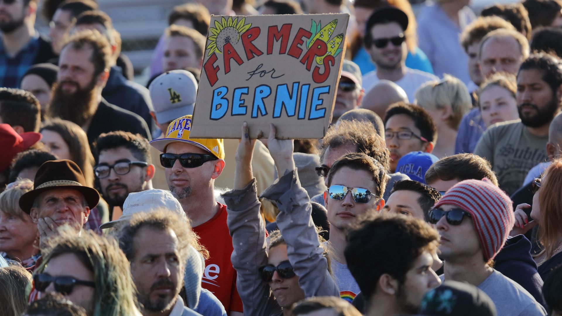 Woman in a crowd holding a farmers for bernie sign