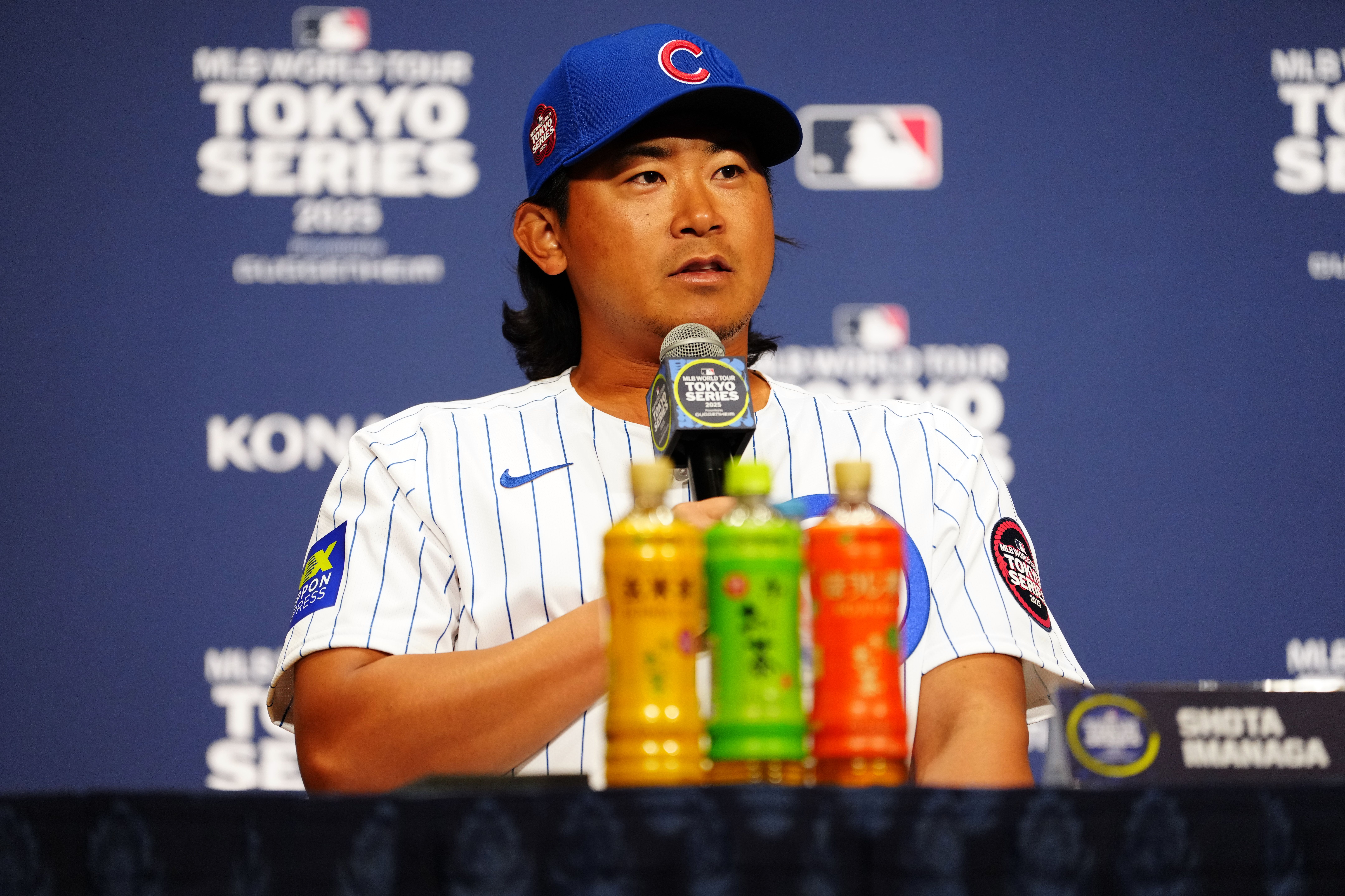 Photo of a baseball player in uniform at a podium talking. 