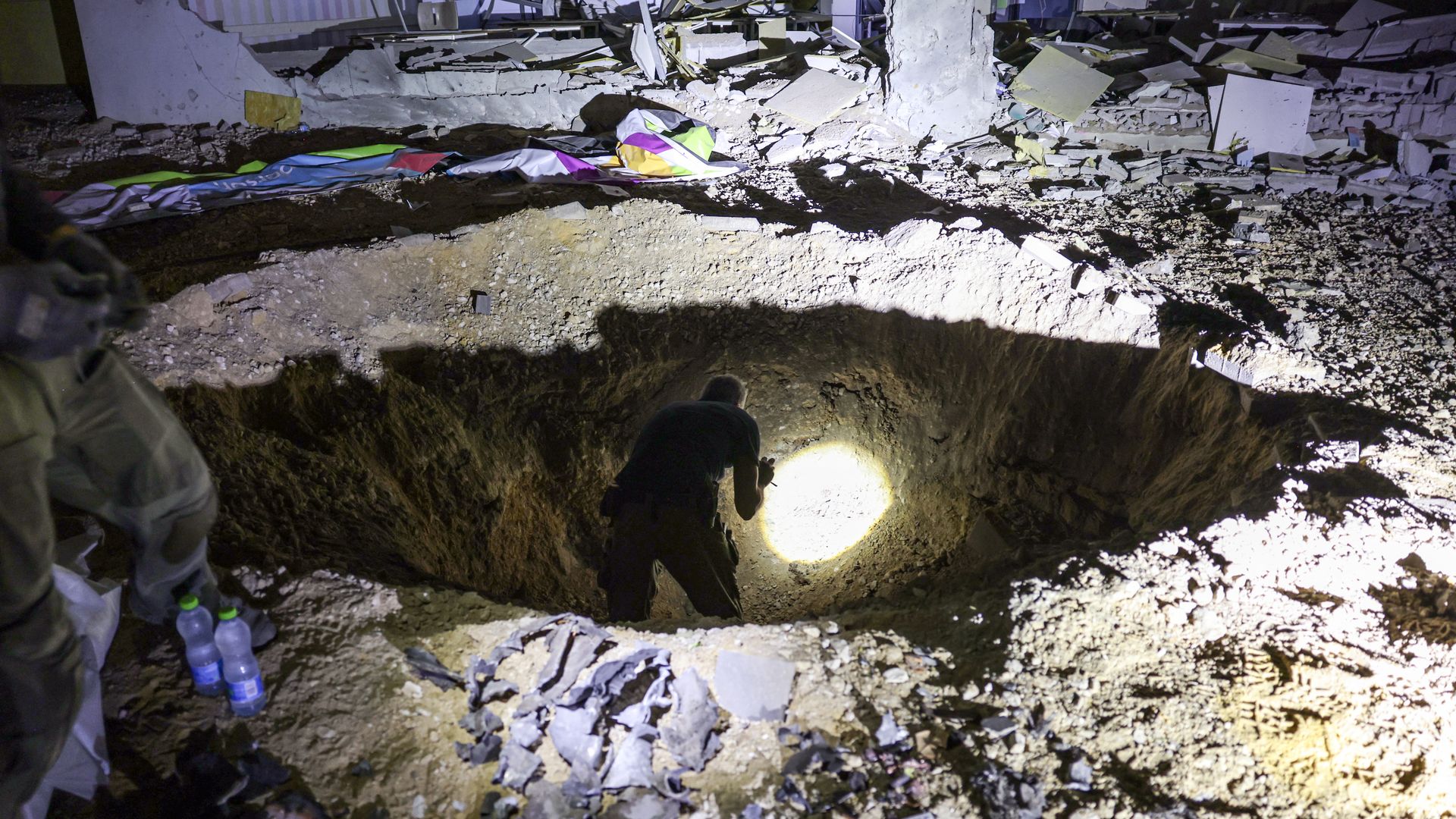 Members of Israel's Home Front Command and police forces inspect a crater left by an exploded projectile at a heavily-damaged school building in Israel's southern city of Gedera on October 1, 2024