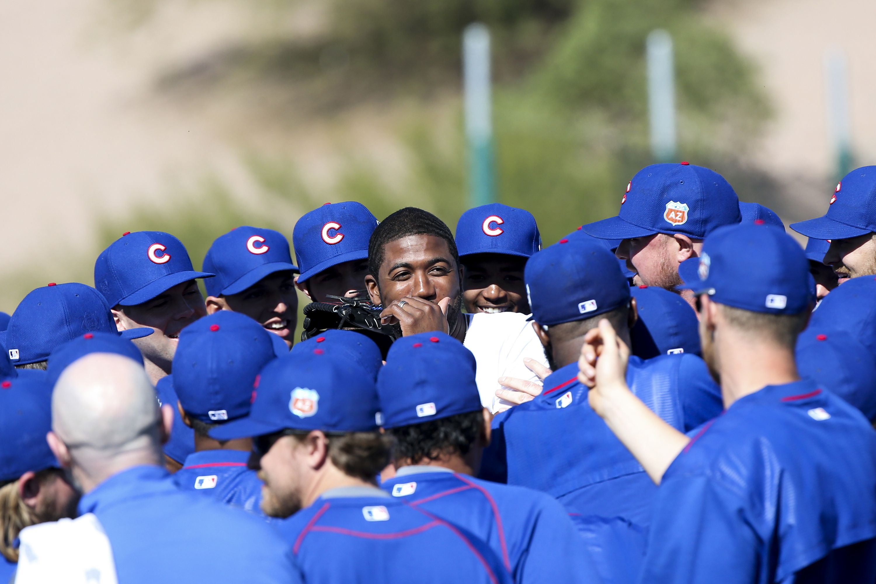Photo of a player being hugged on a baseball diamond by teammates. 
