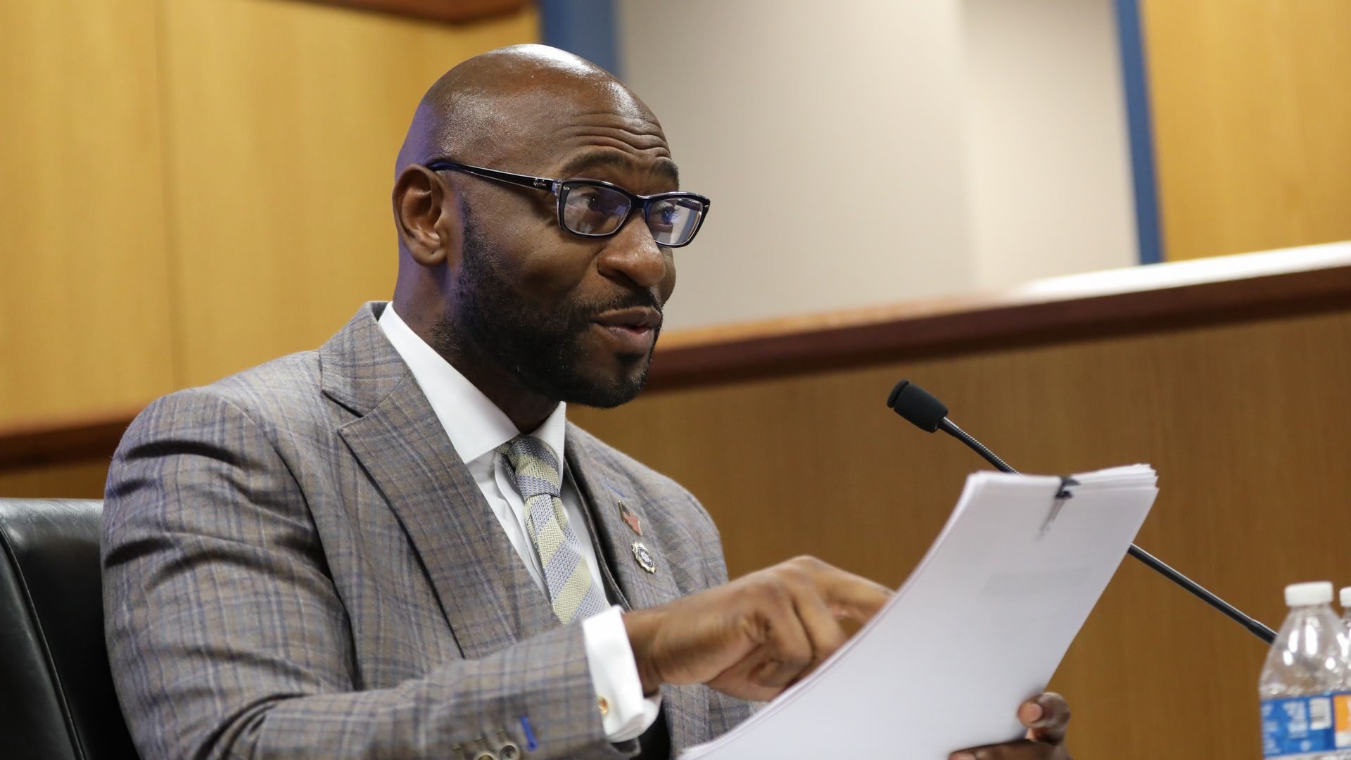 Nathan Wade sits in court reading from a paper into a microphone. He is wearing a gray suit and glasses. 