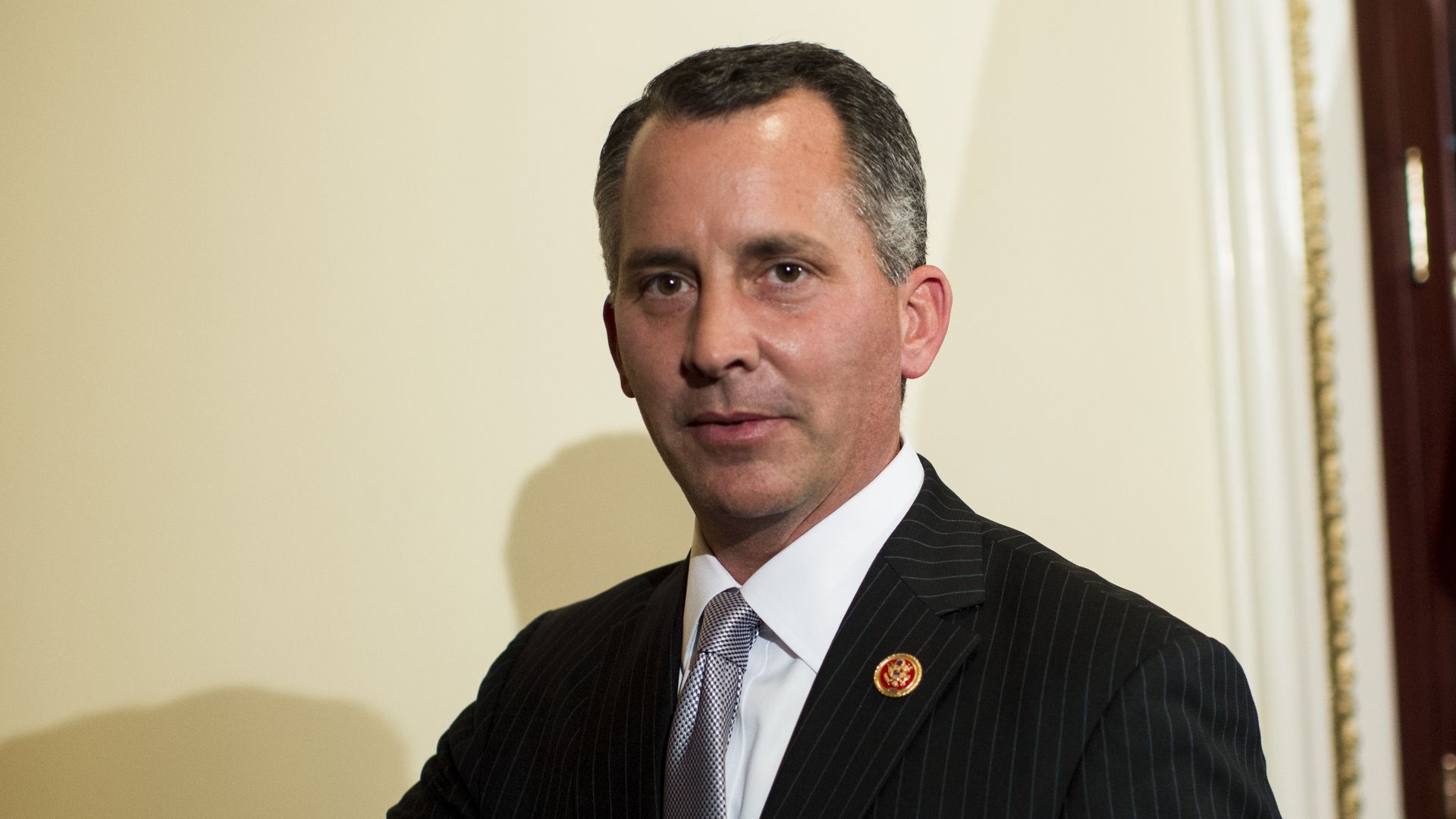 Rep. David Jolly, wearing a gray pinstripe suit and standing in front of a cream-colored wall.