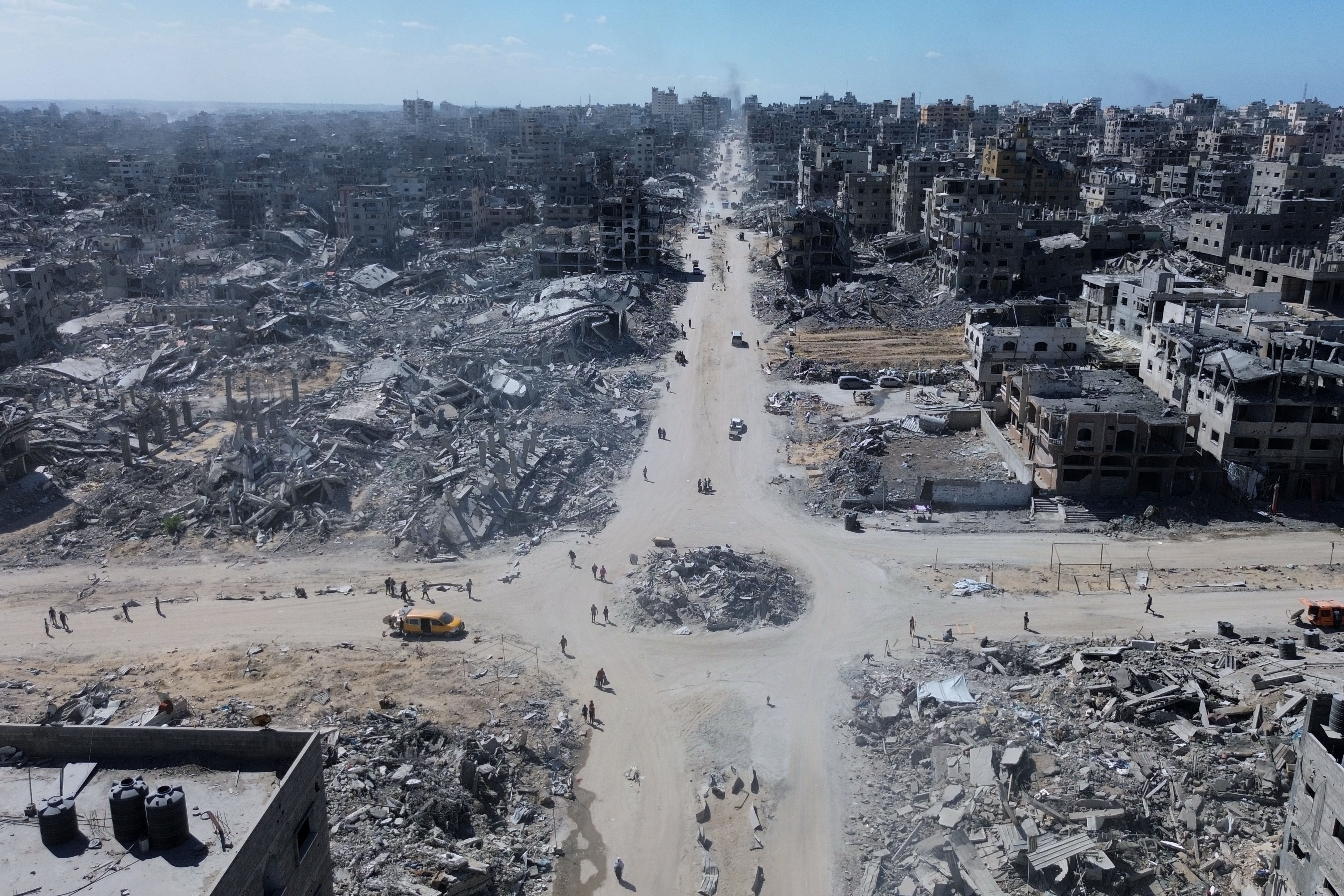 Palestinians walk in an intersection surrounded by destroyed buildings in Gaza City yesterday.