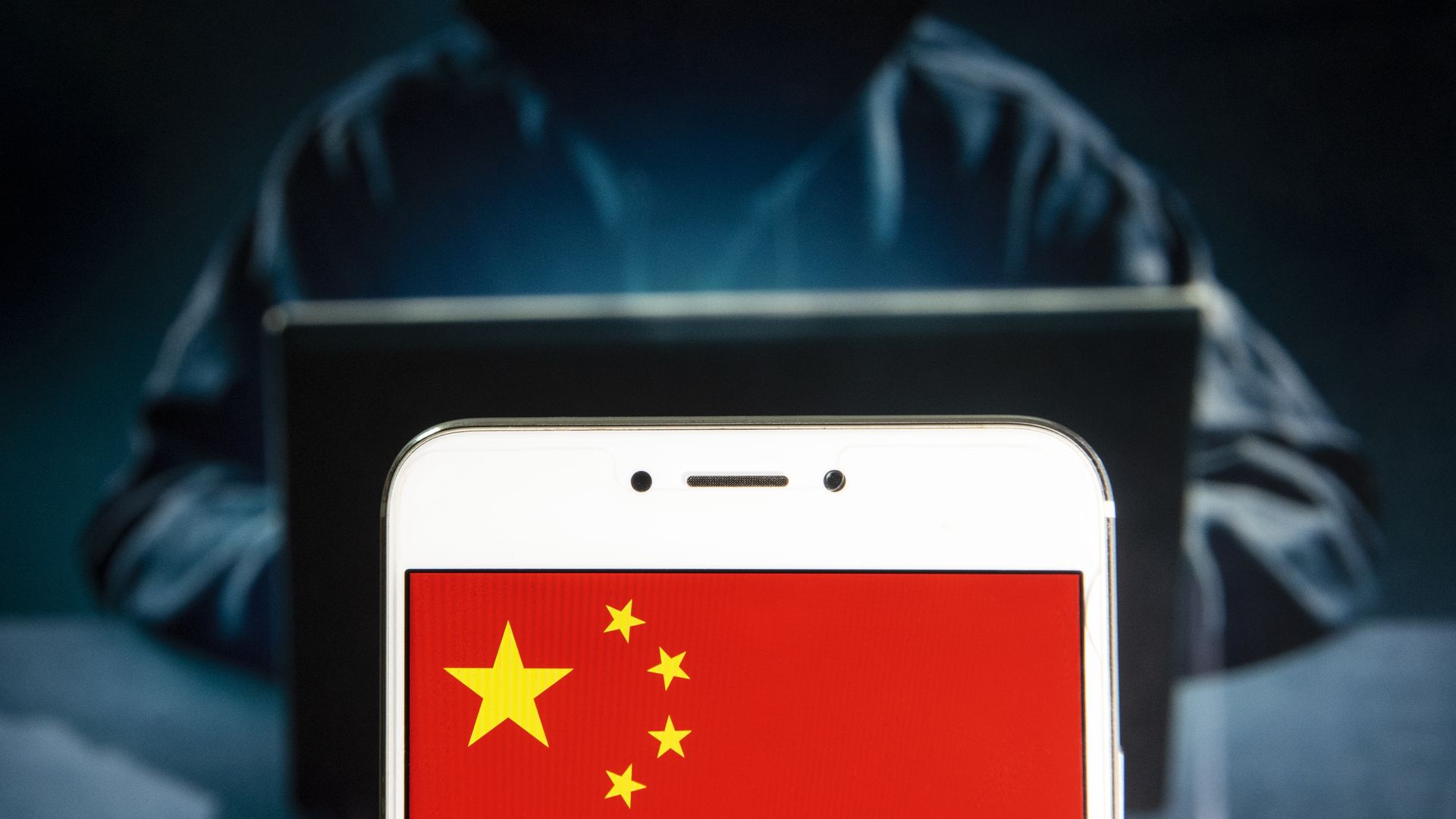 In this photo illustration, a People's Republic of China flag is seen on an Android mobile device with a figure of hacker in the background.