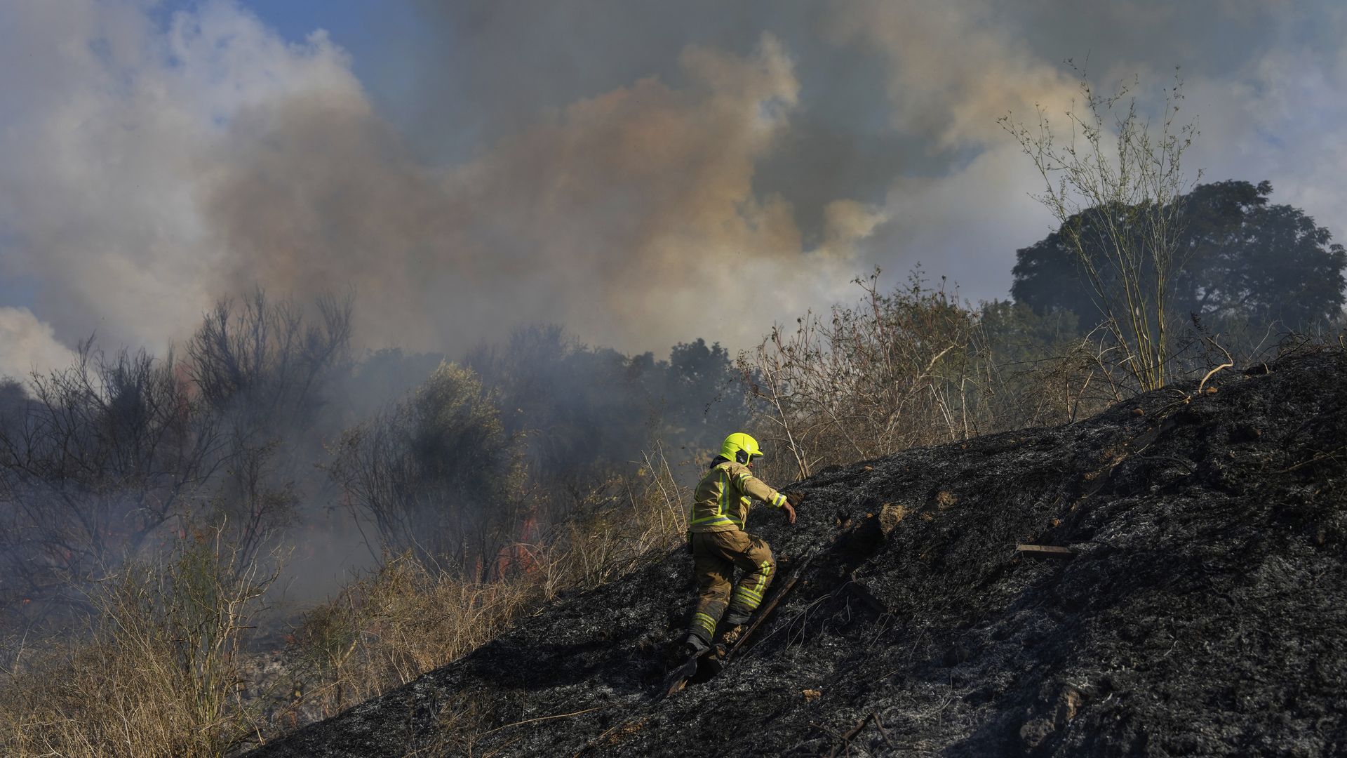 A firefighter works in the area around a fire after the military said it fired interceptors at a missile launched from Yemen that landed in central Israel on Sunday, Sept. 15, 2024. (AP Photo/Ohad Zwigenberg)