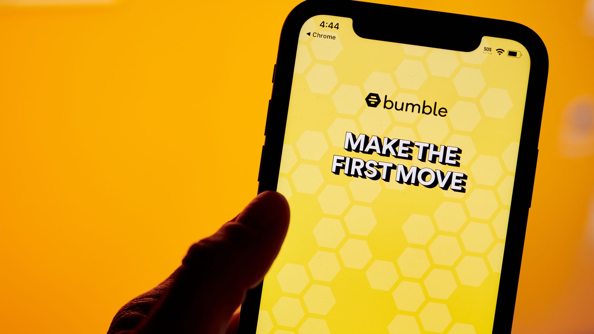 A hand holds a smartphone with the yellow Bumble app open and the phrase "make the first move"