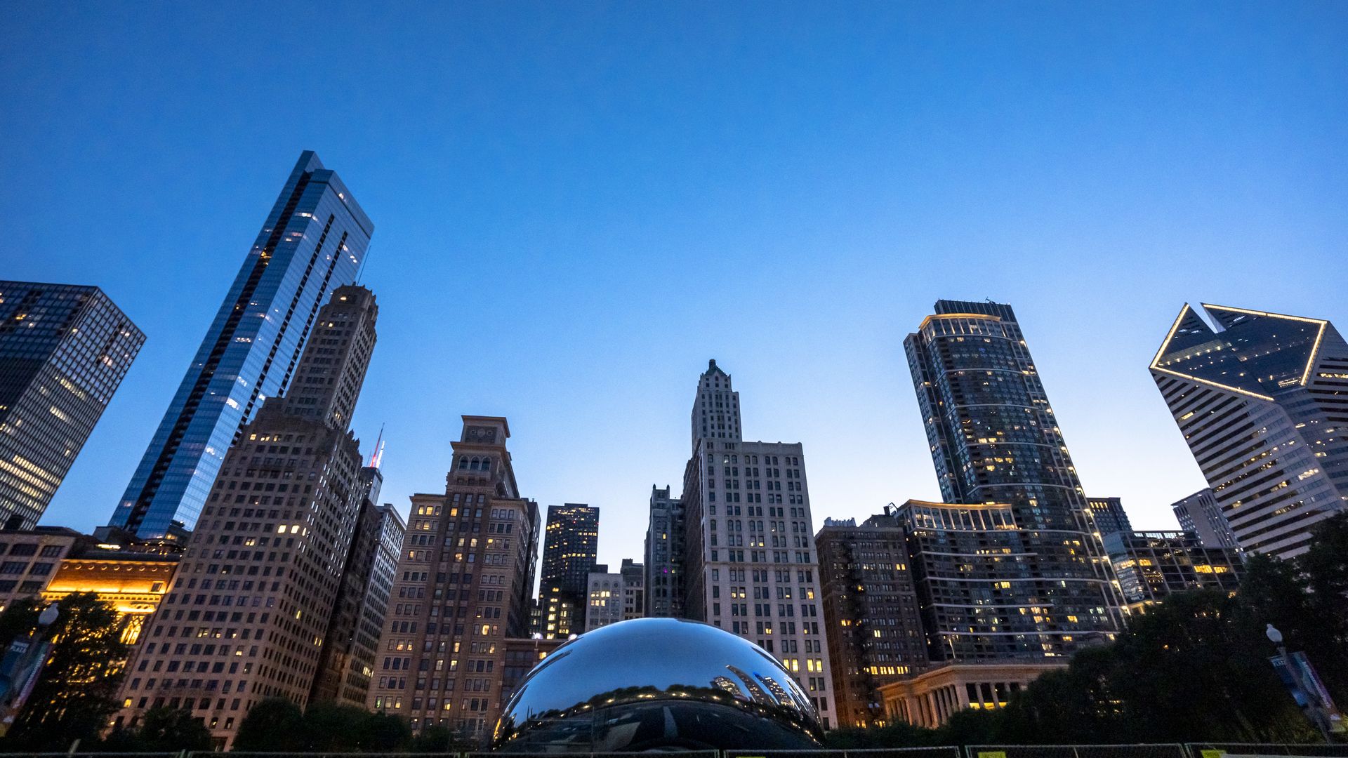 Photo of a bean-like sculpture in front of several high-rise skyscrapers in a city. 