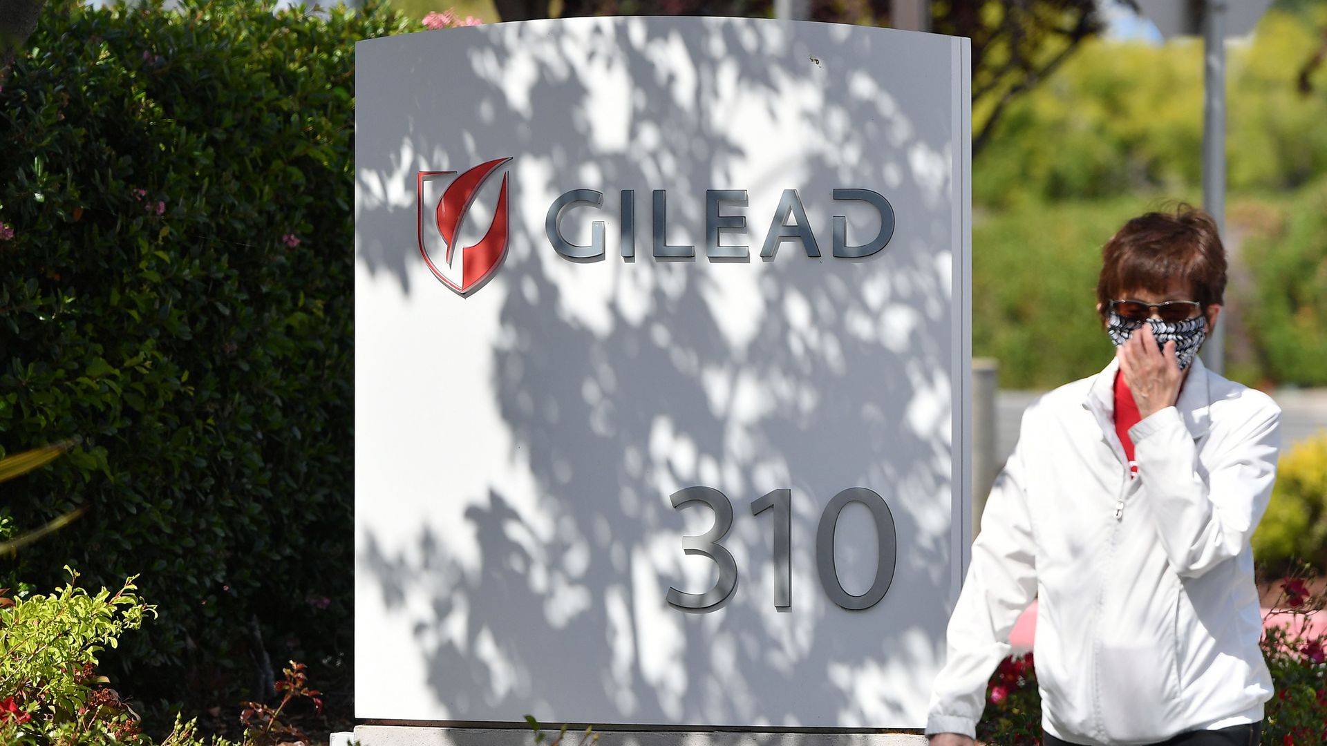 A woman wears a mask near a white Gilead headquarters sign.
