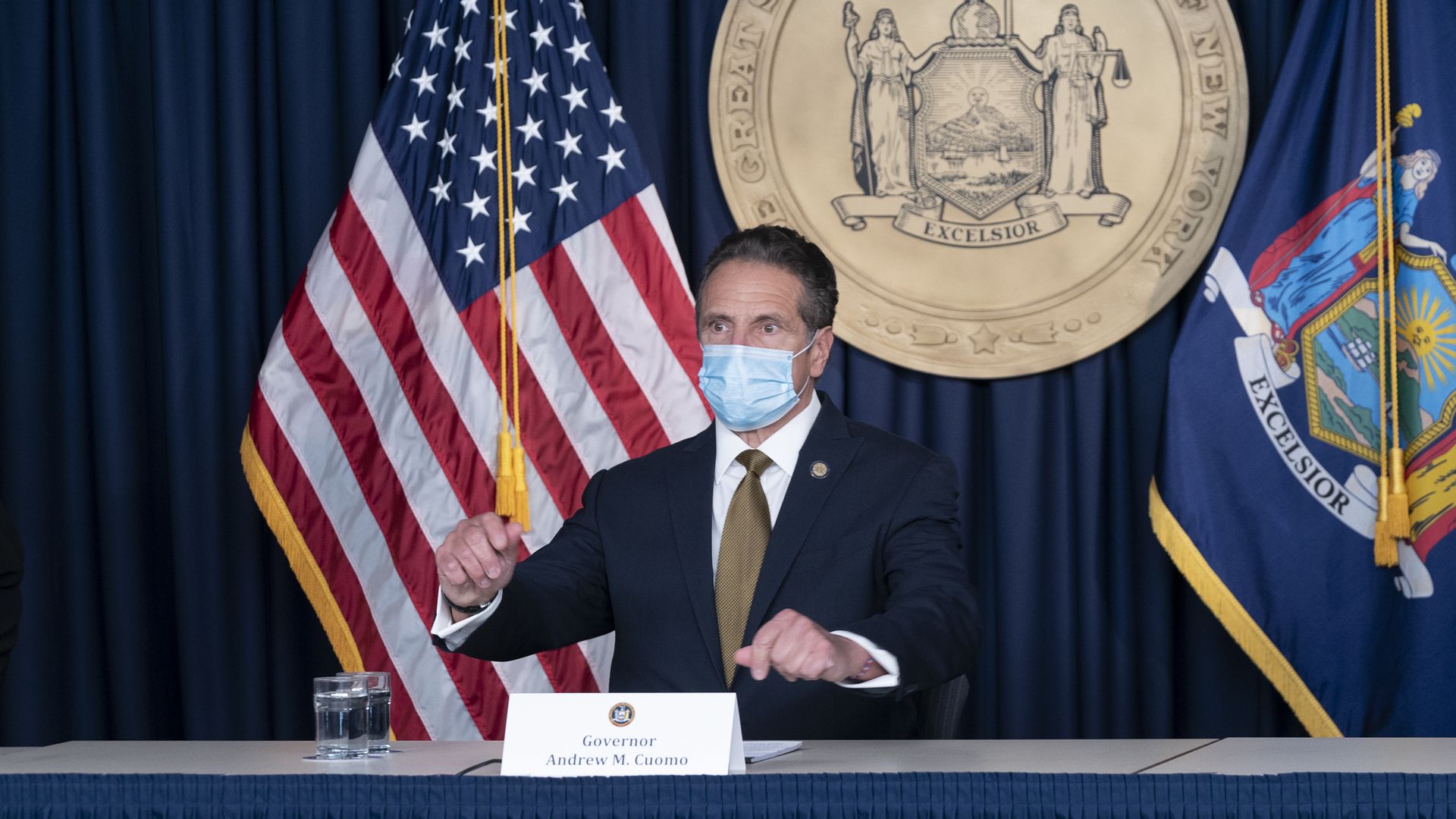 Andrew Cuomo wears a face mask in front of an American flag 