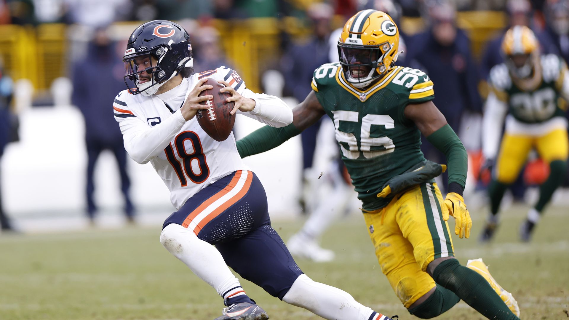 Photo of a football player in a uniform chasing another football player who has the ball during a game. 