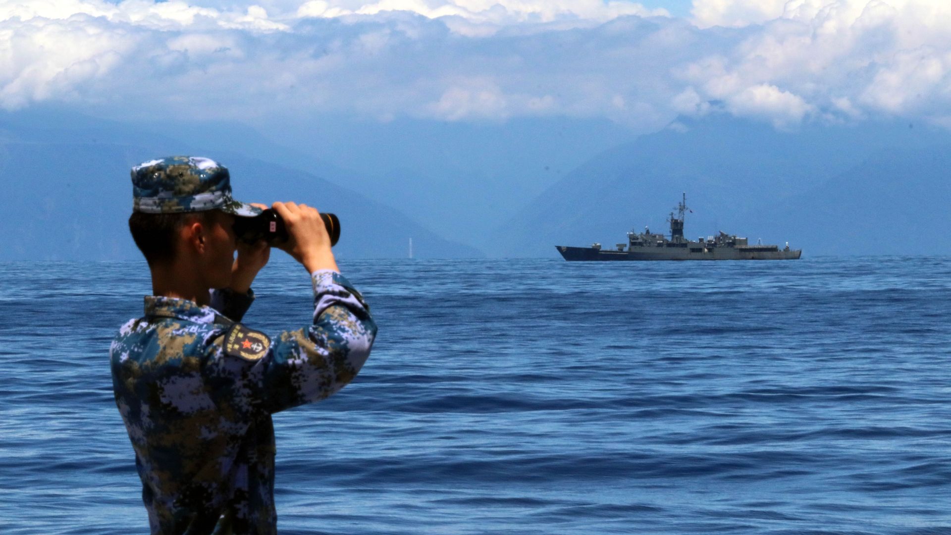 A soldier looks through binoculars during combat exercises off Taiwan coast