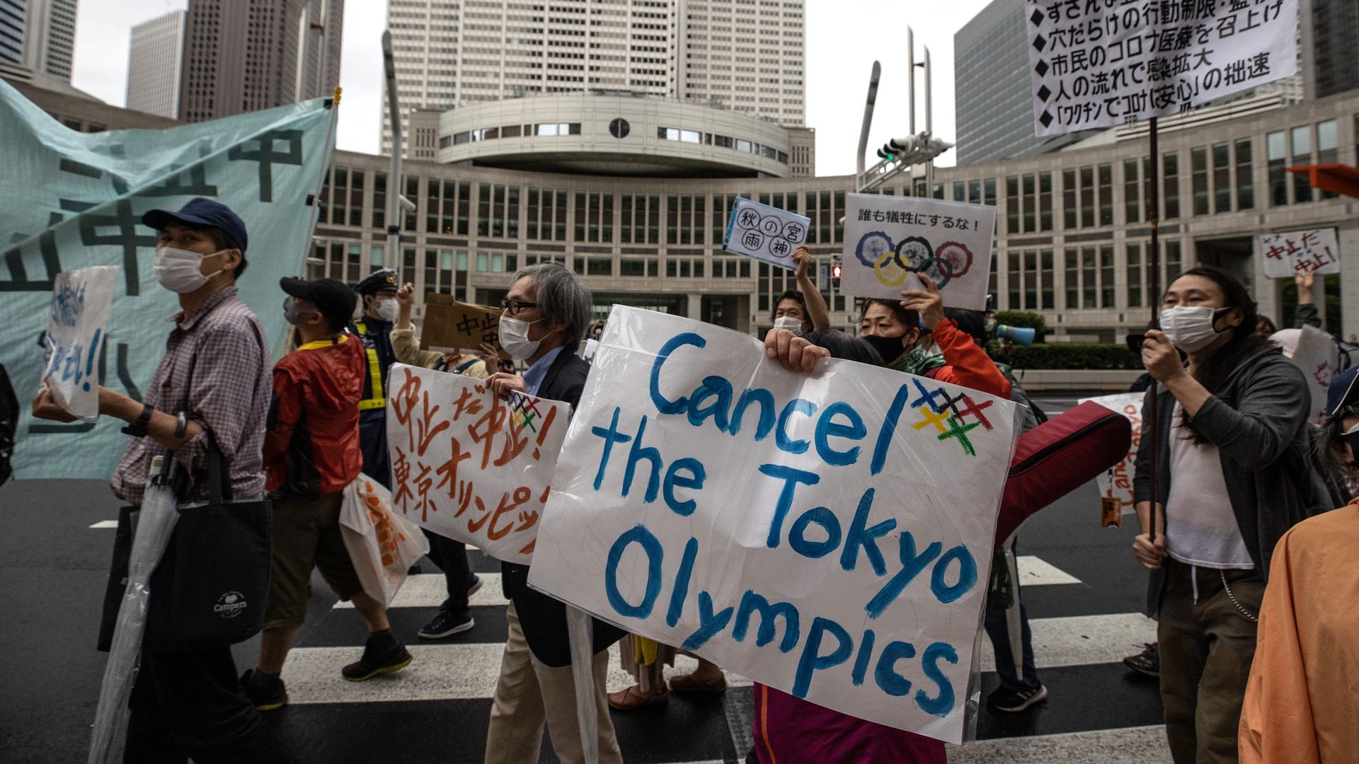 Picture of group of people protesting against the Olympics in Tokyo, with one sign that reads "Cancel the Tokyo Olympics"