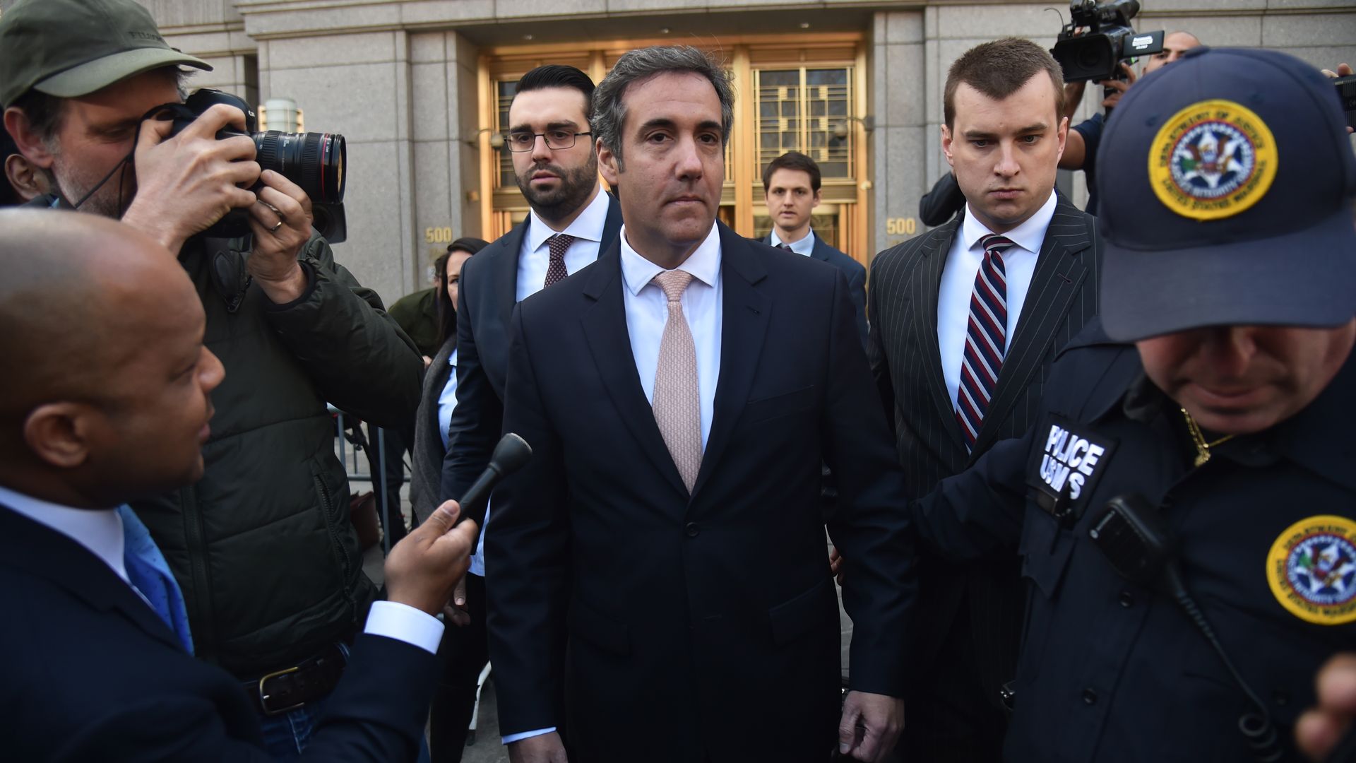Cohen surrounded by camera and security after leaving a NY courthouse