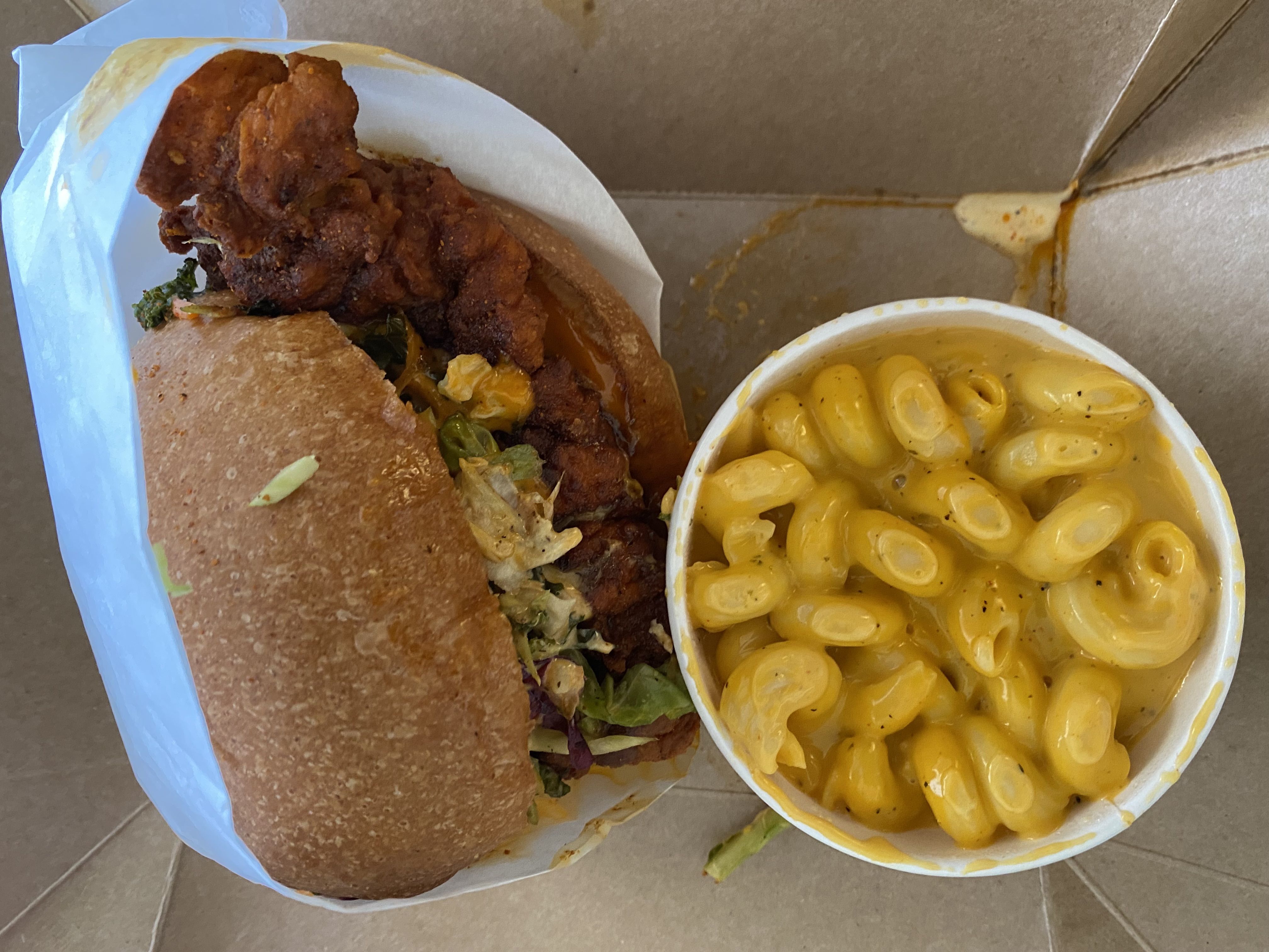 A hot chicken sandwich with a side of mac and cheese