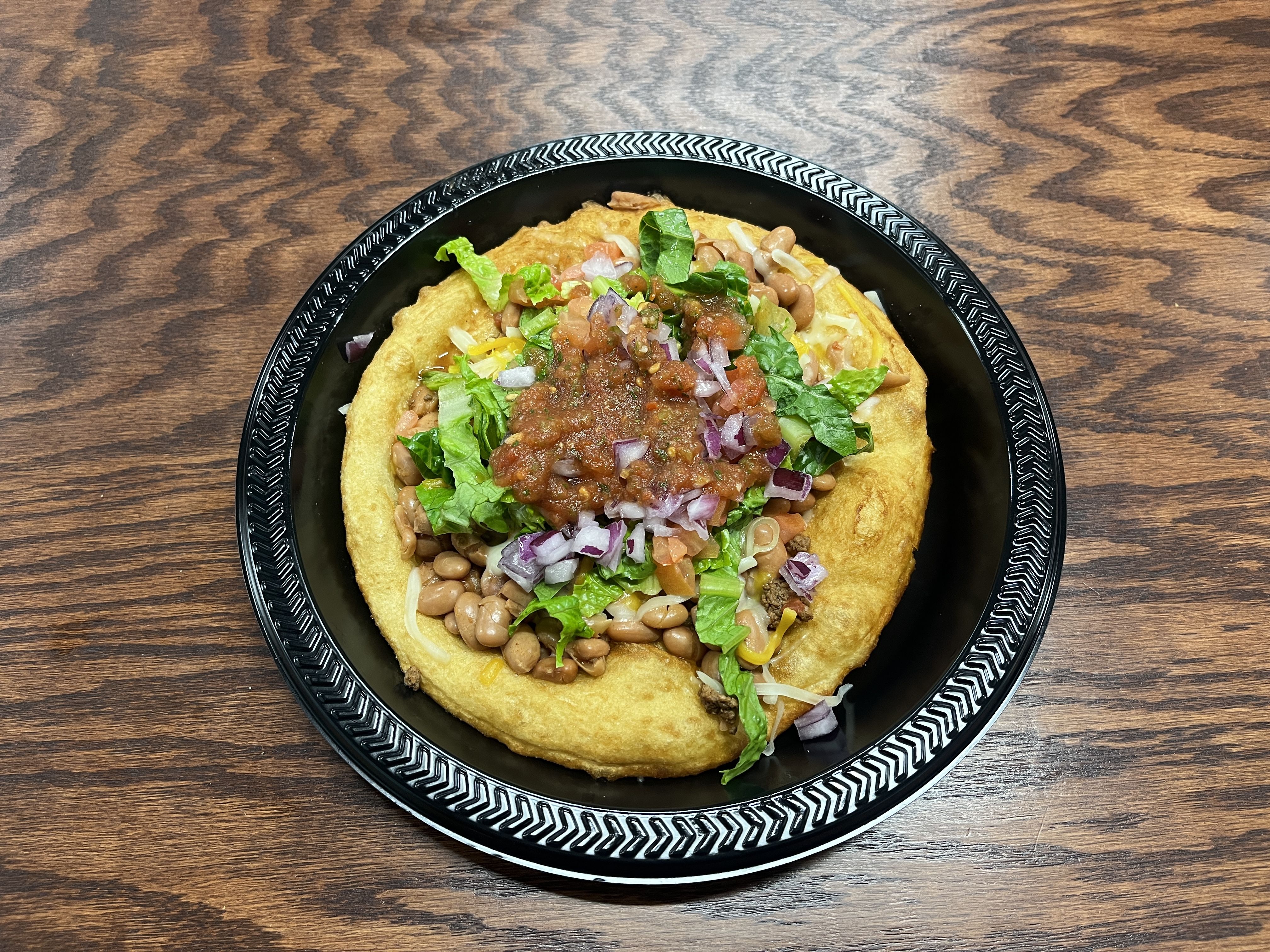 A round fry bread topped with beans and salsa.
