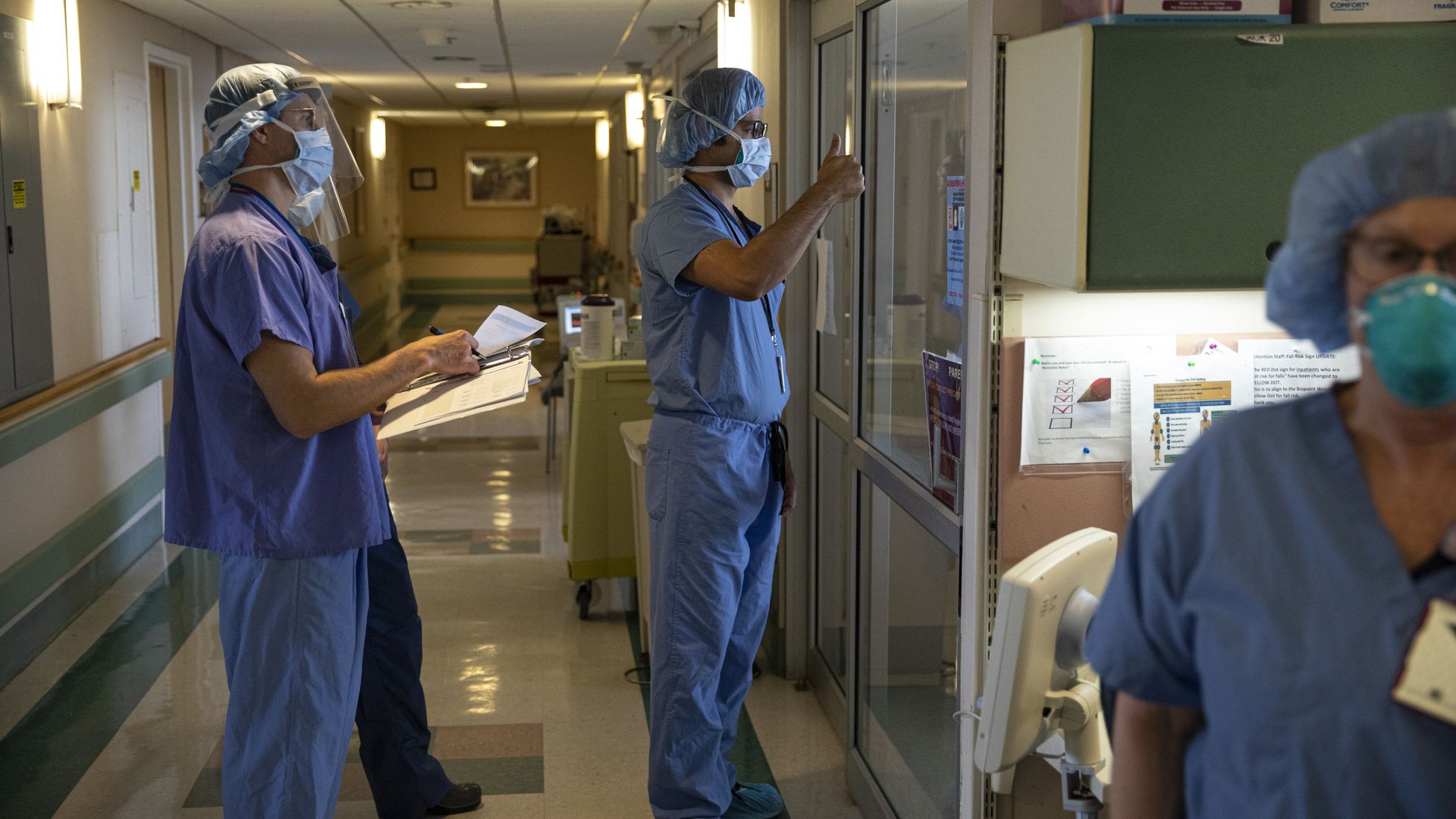 A medical doctor (C) gives the thumbs-up sign to a COVID-19 patient who is no longer using a respirator.