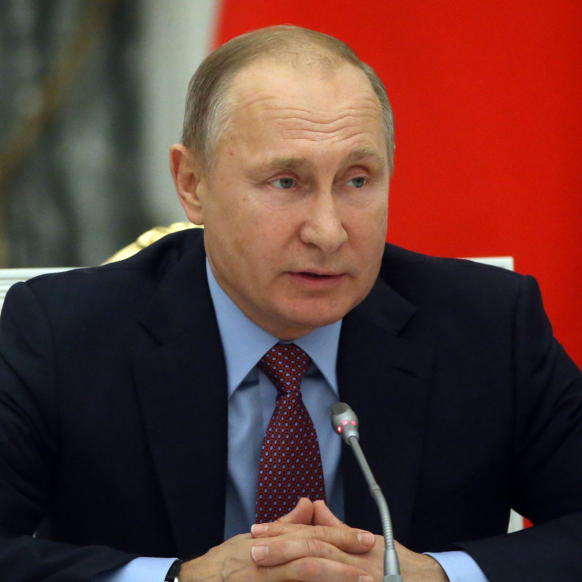 Vladimir Putin seated at microphone during meeting