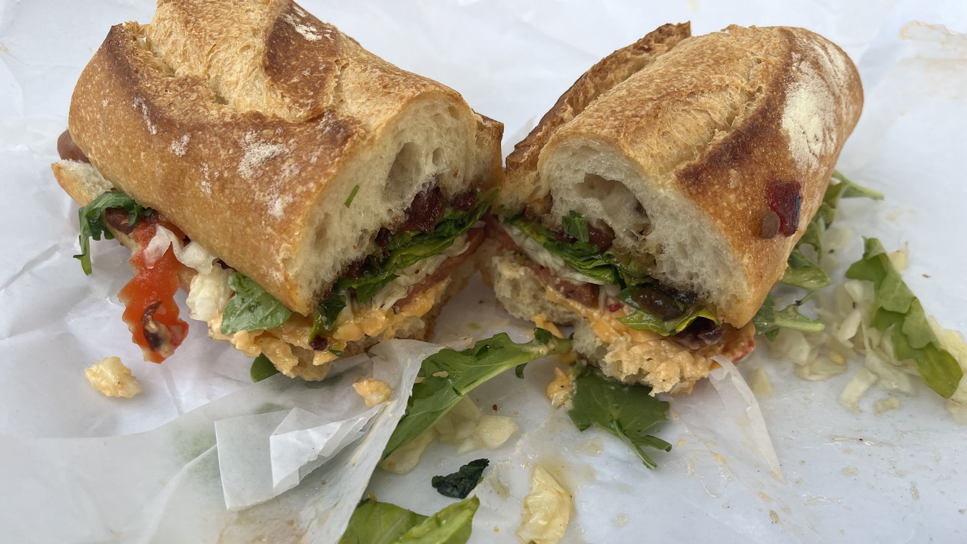 A baguette sandwich with pimento cheese, brisket, greens and sweet peppers