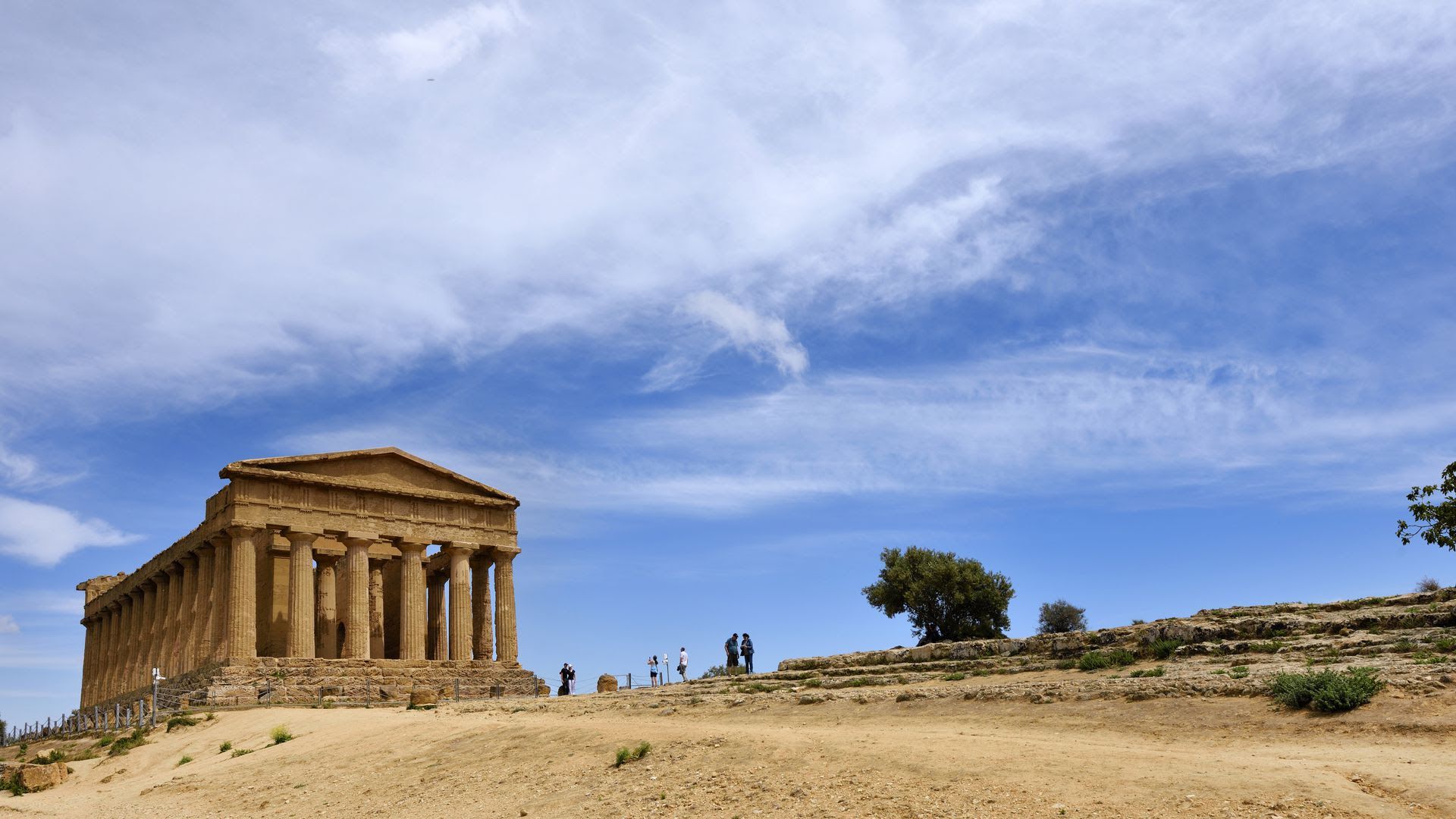 Temple of Concord in Agrigento, Italy, in front of a blue sky.