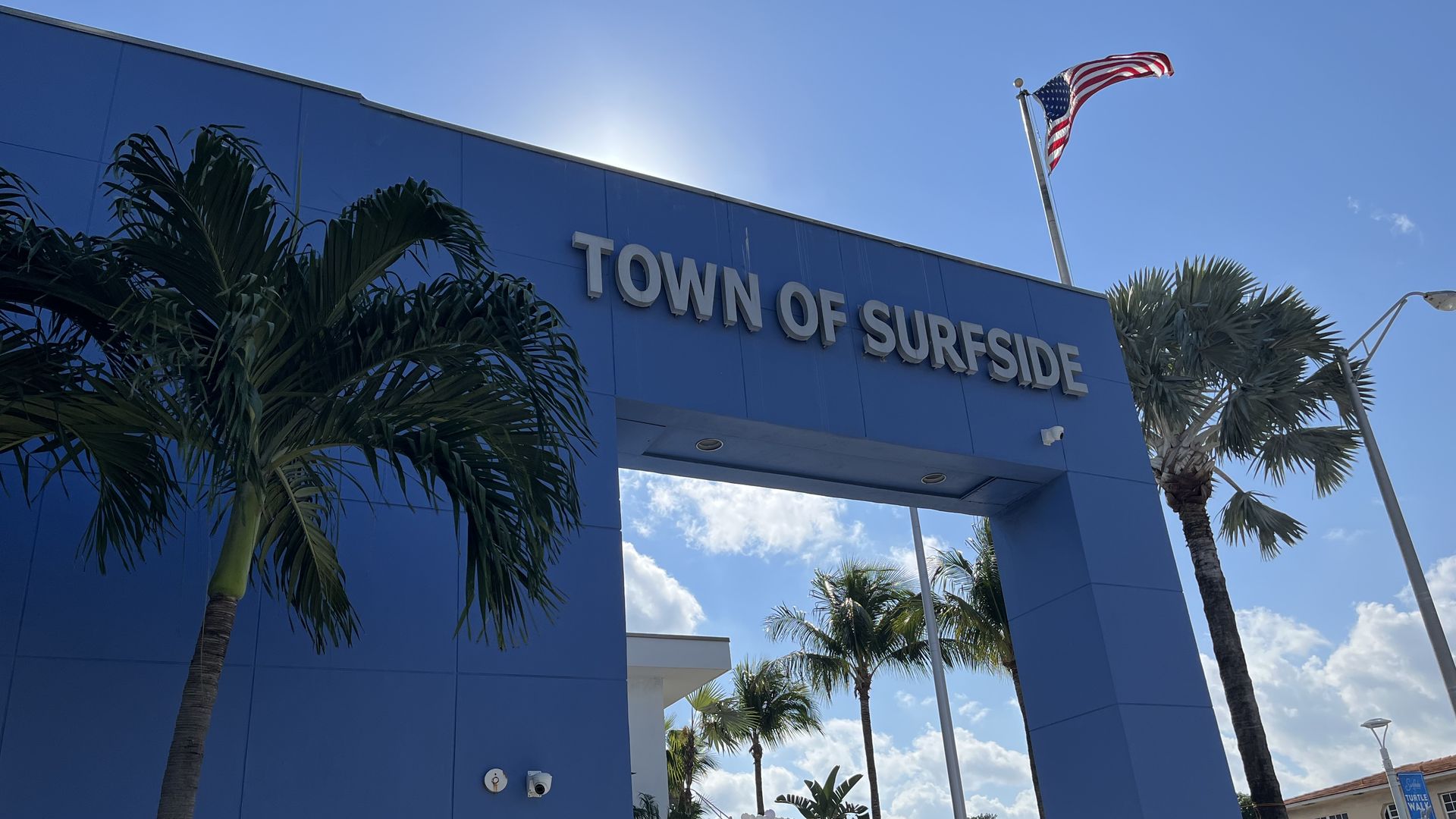 Surfside Town Hall is pictured, with an American flag and palm trees in view.