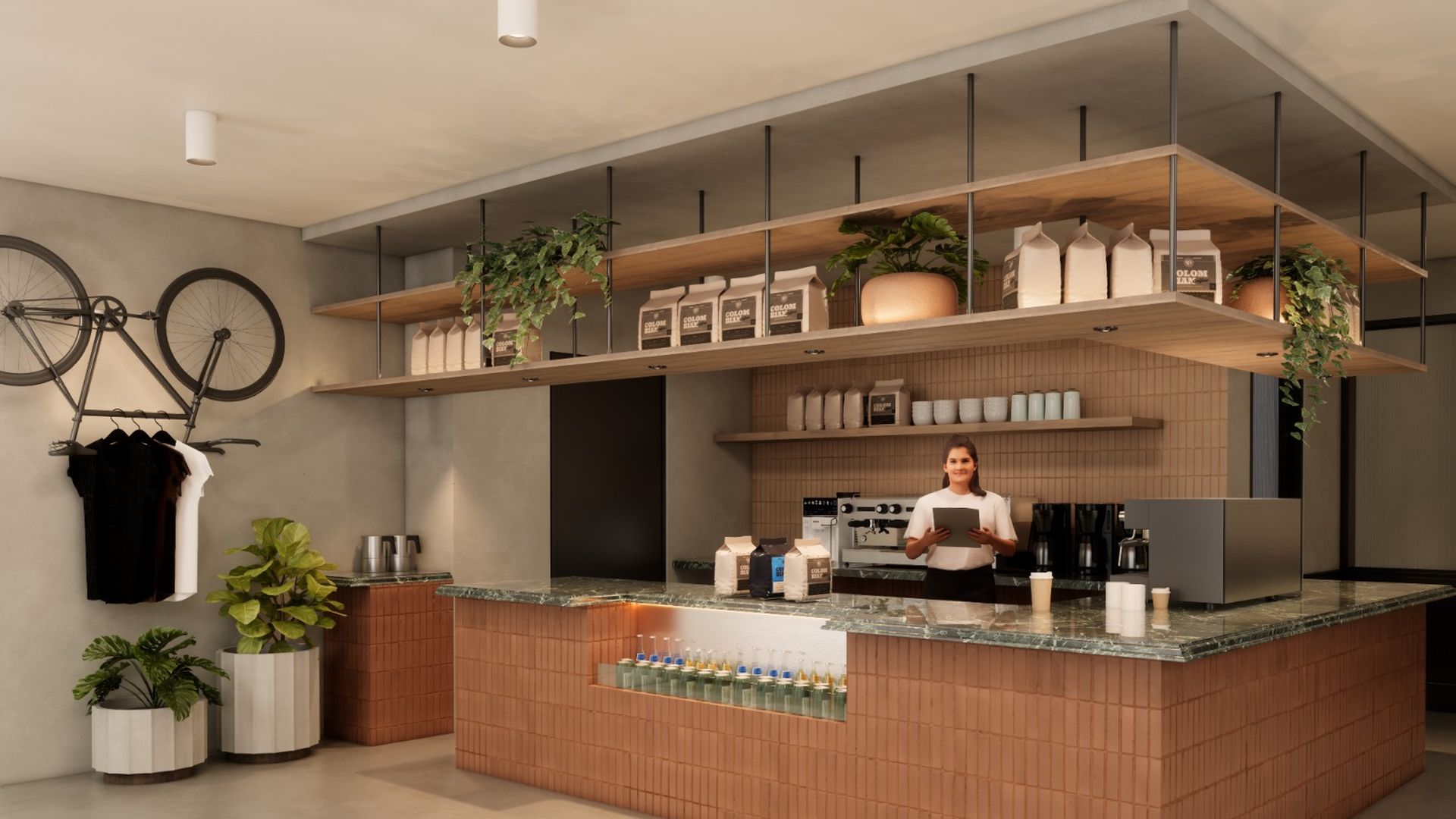 Modern coffee shop interior with terracotta tiled counter, green marble countertop, hanging shelves with plants and milk cartons, barista behind counter, bike and clothes on wall.