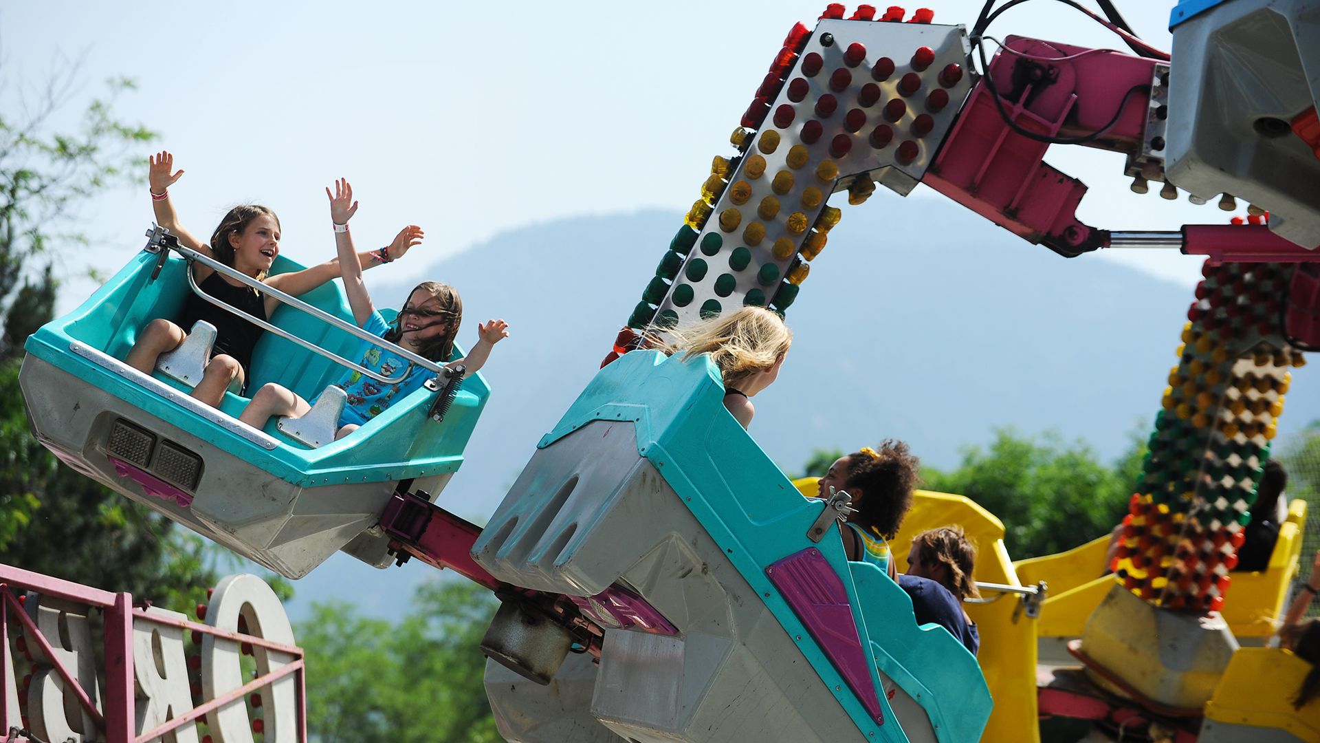 Two kids raise there hands while on a carnival ride at the Boulder Creek Festival