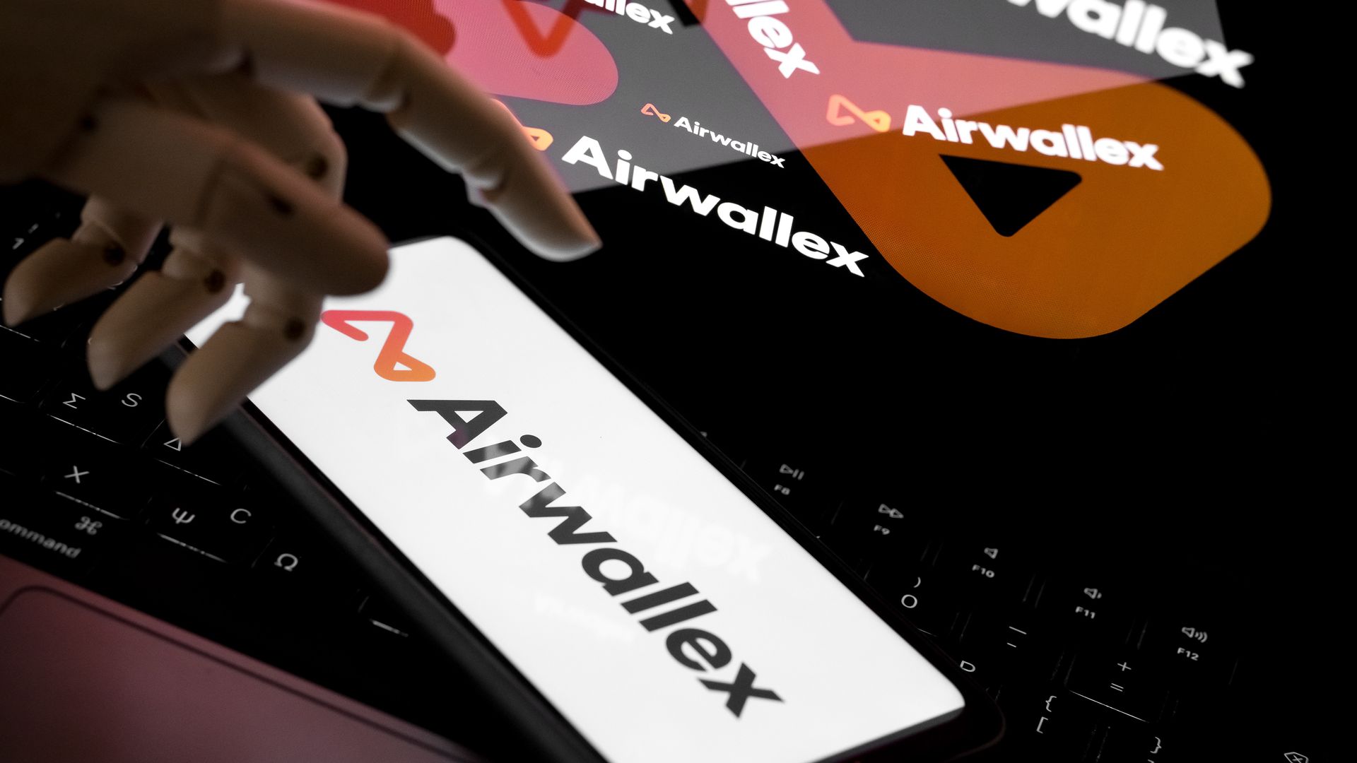 The Airwallex logo appears on a smartphone screen and as the background on a laptop computer screen in this photo illustration