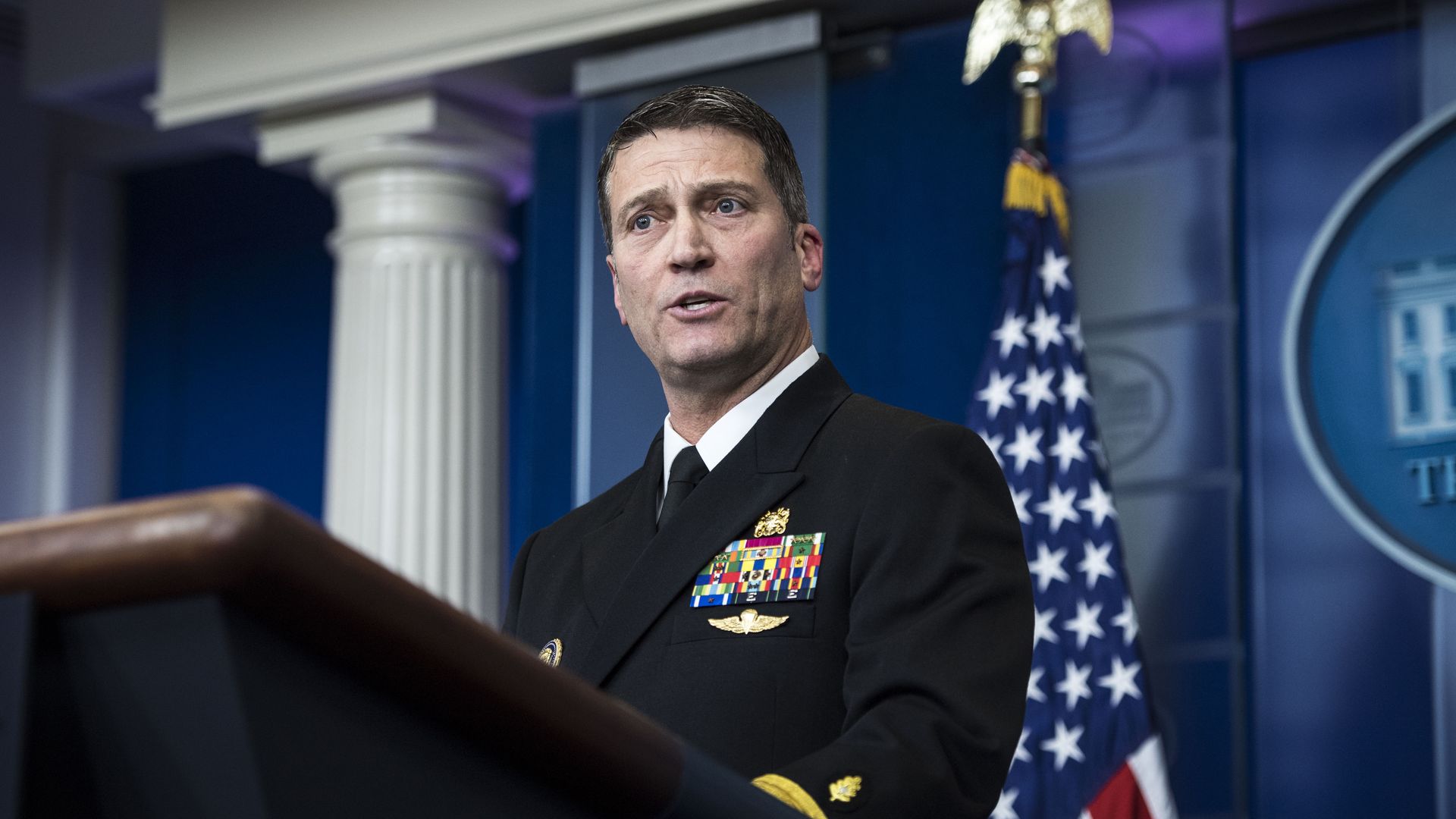 Ronny Jackson speaks behind a podium in the White House briefing room