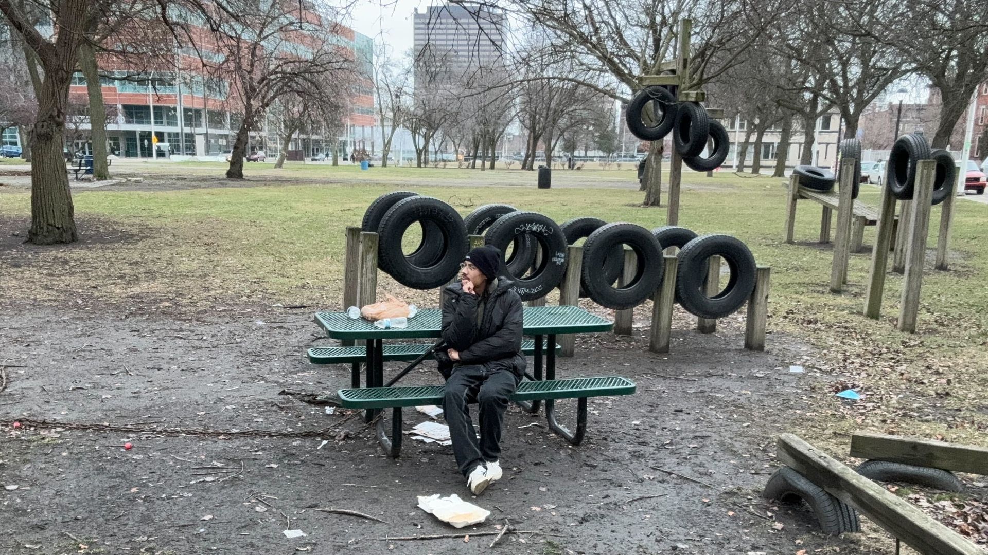 Sam sits in the park on a picnic table.