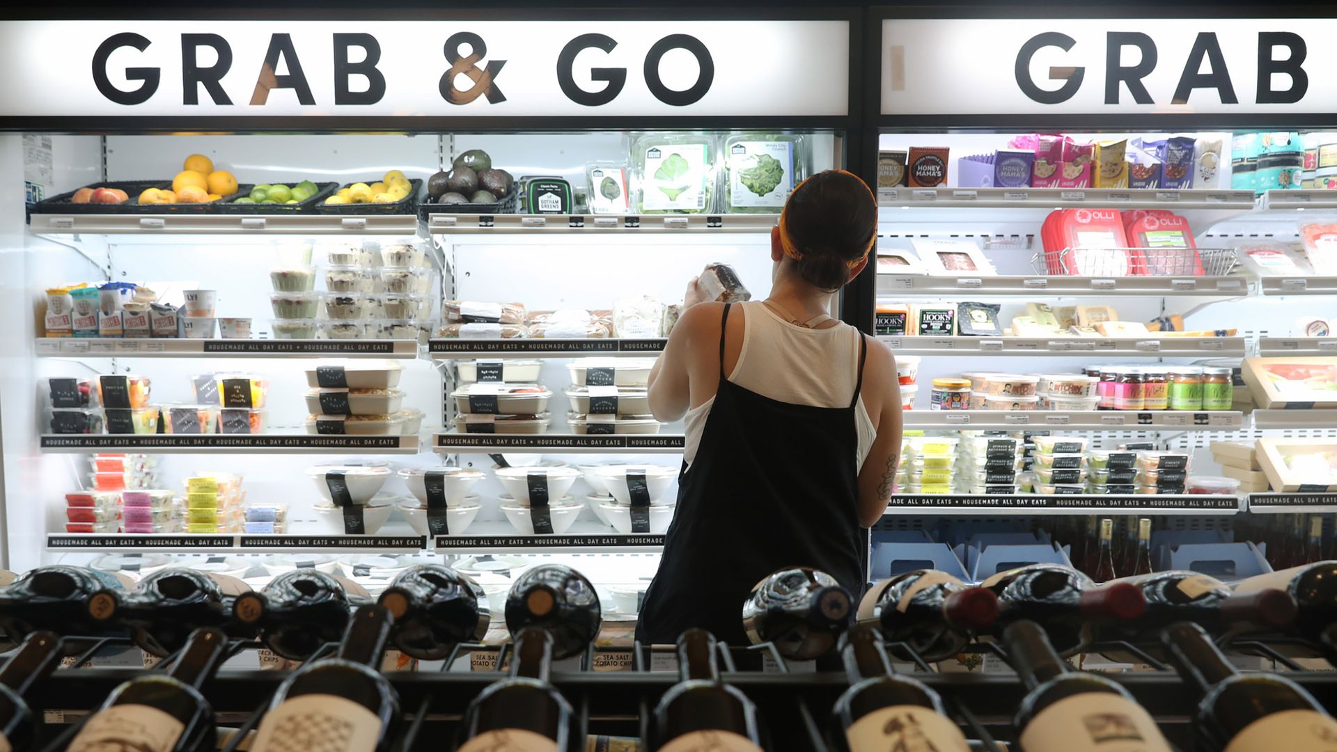 A photo of a person standing in front of a fridge with the words "Grab & Go"