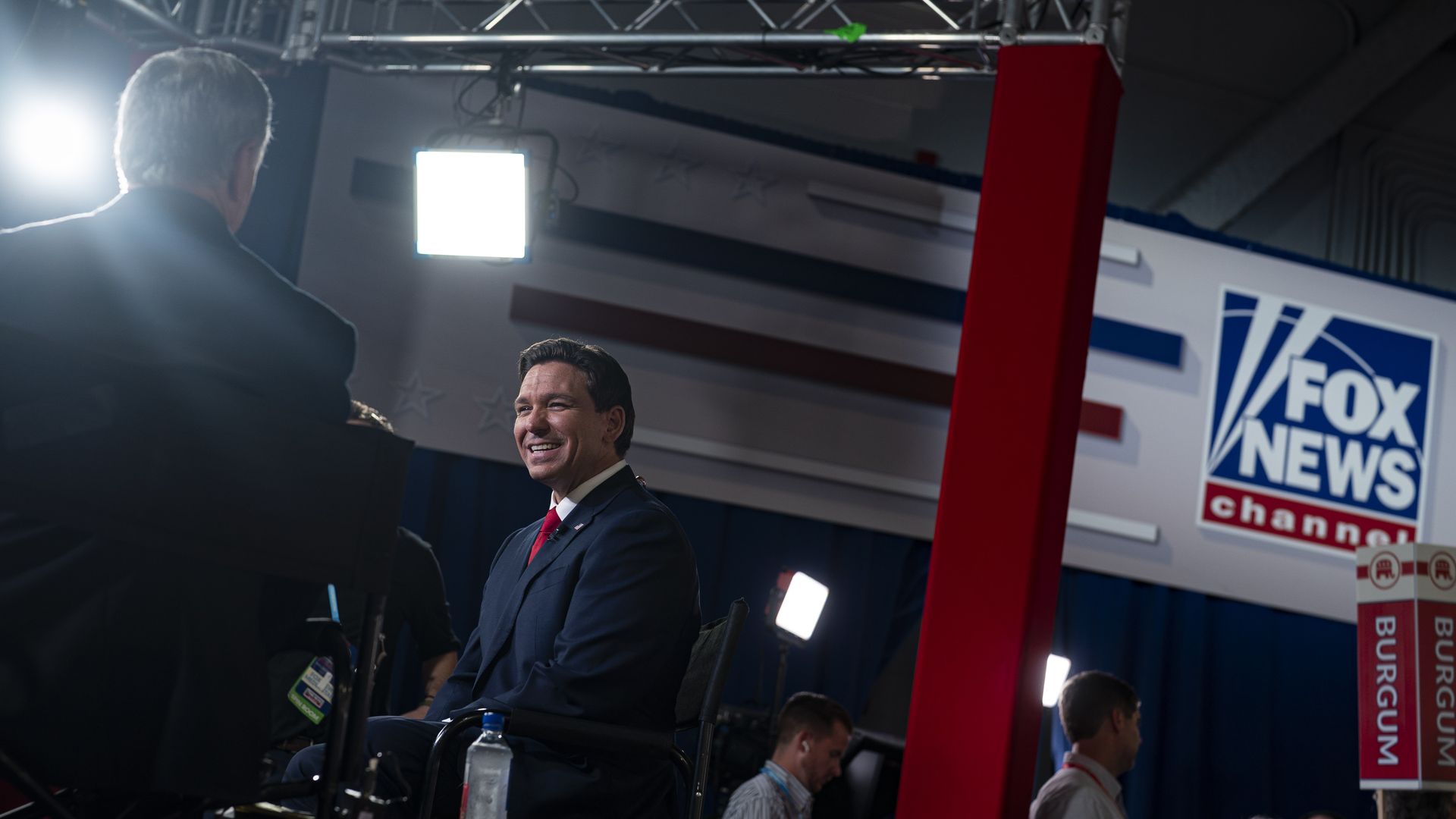 Ron DeSantis and Sean Hannity speak. Hannity's back is to the camera. DeSantis is smiling facing him. The FOX News logo is in the background. 