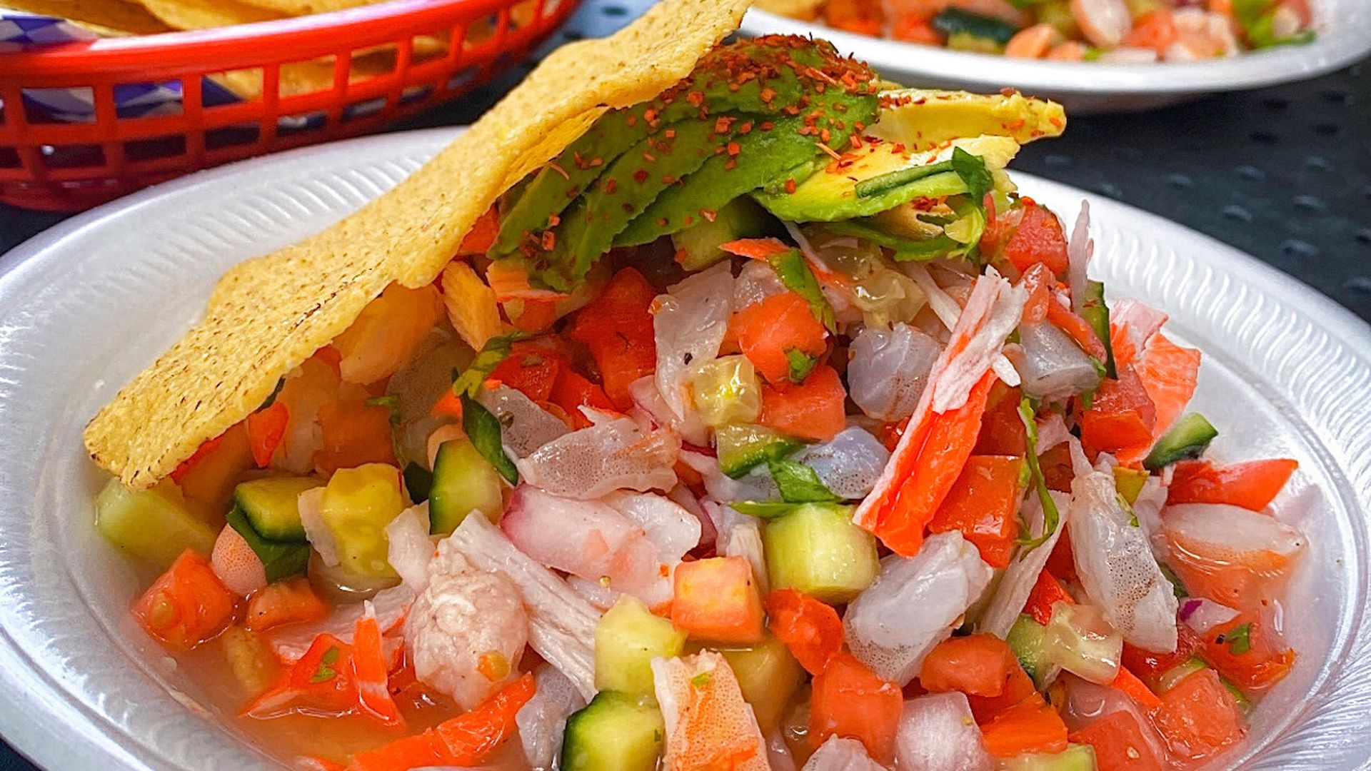 Two plates of fresh ceviche mix, topped with avocado and tortilla chips.