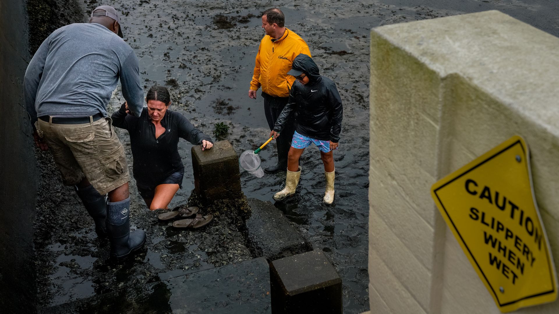 A woman gets help climbing from a muddy area in Tampa, Florida, United States on September 28.