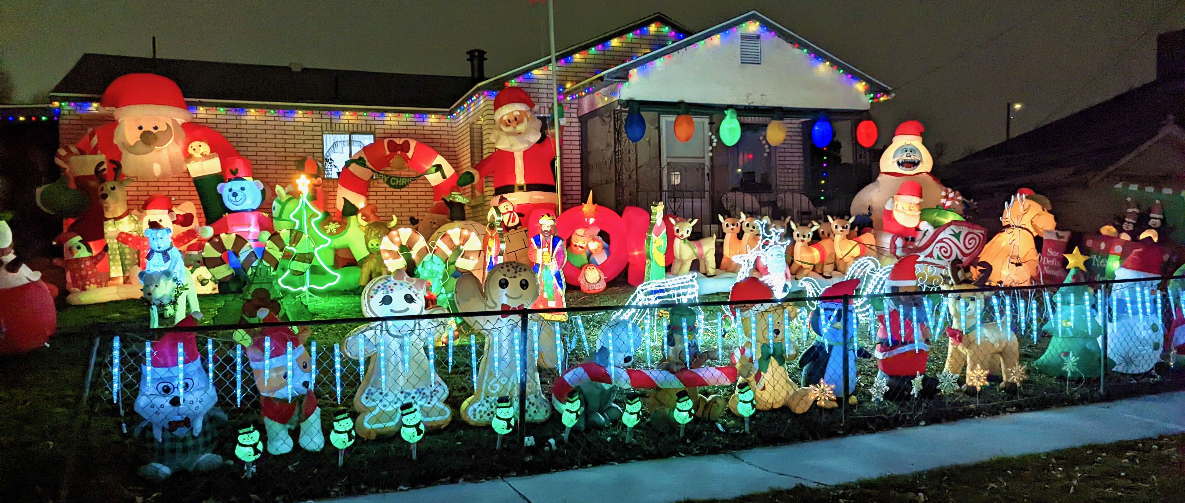 A house with inflatables decorations in the yard showing Santa, the abominable snowman, Christmas trees, reindeer, snowmen, gingerbread figures and other seasonal items.
