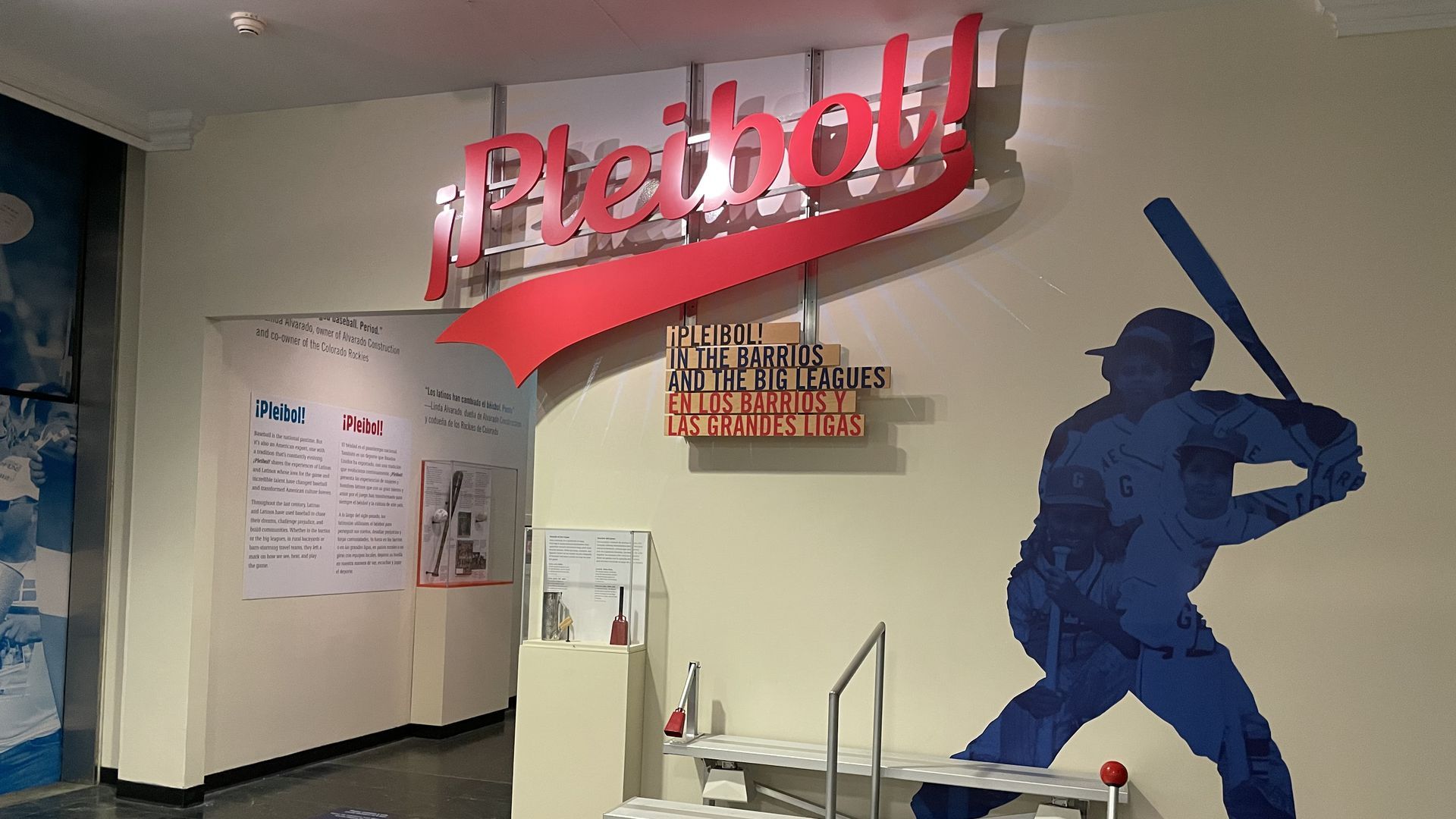 The blue silhouette of a baseball batter sits to the right of a red sign with the word "¡Pleibol!"